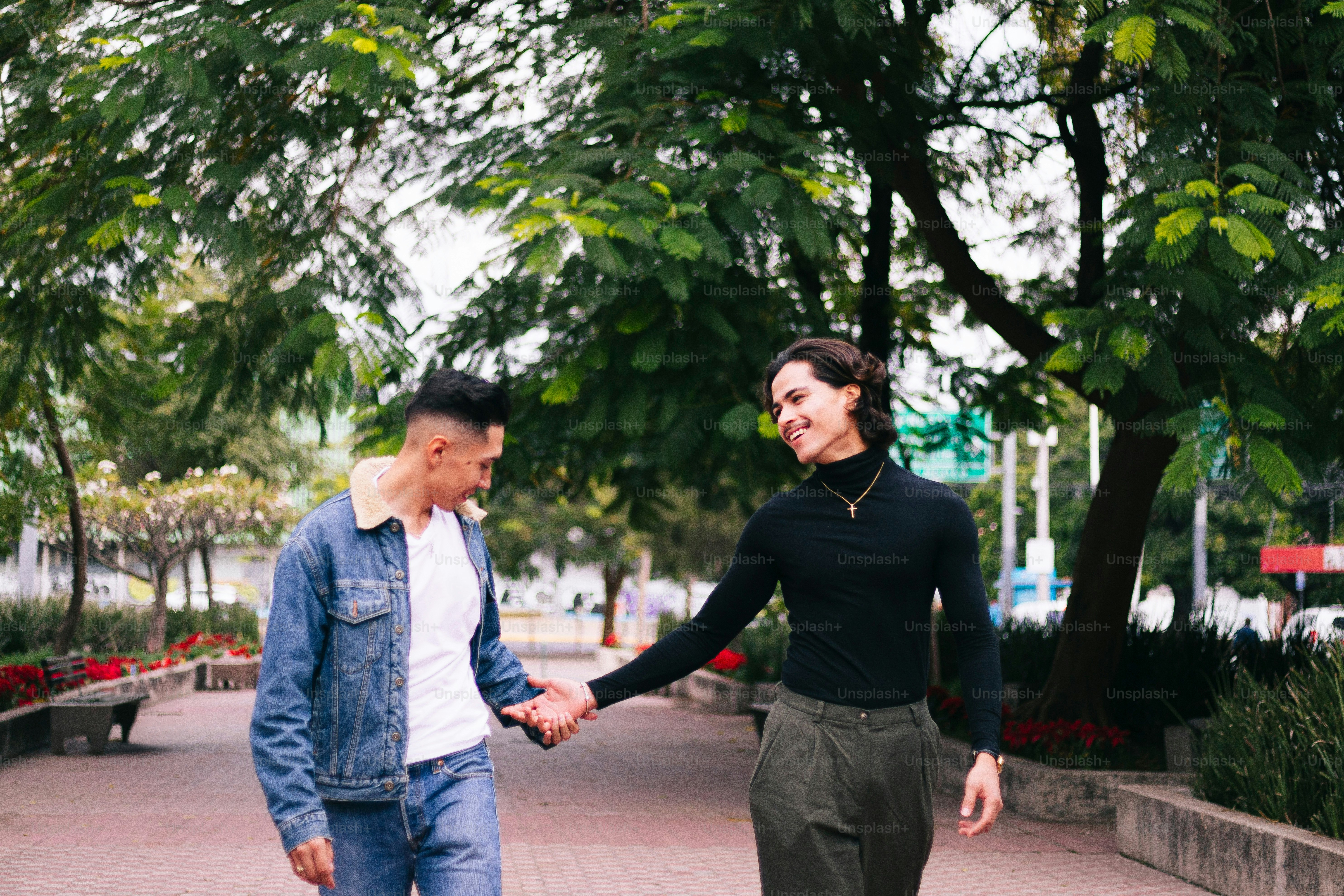 A man and a woman holding hands walking down a sidewalk