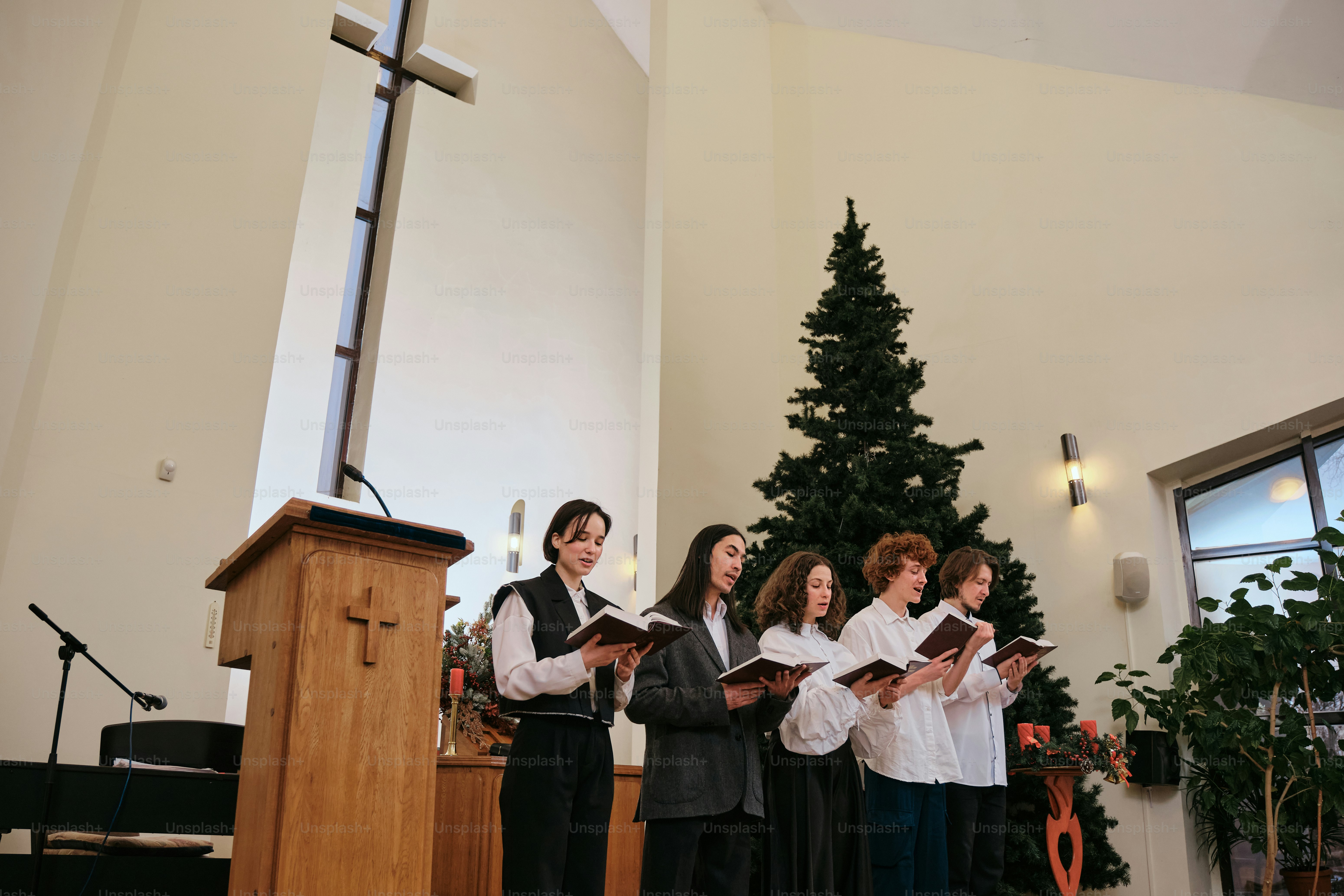 Um grupo de pessoas cantando na frente de uma árvore de Natal