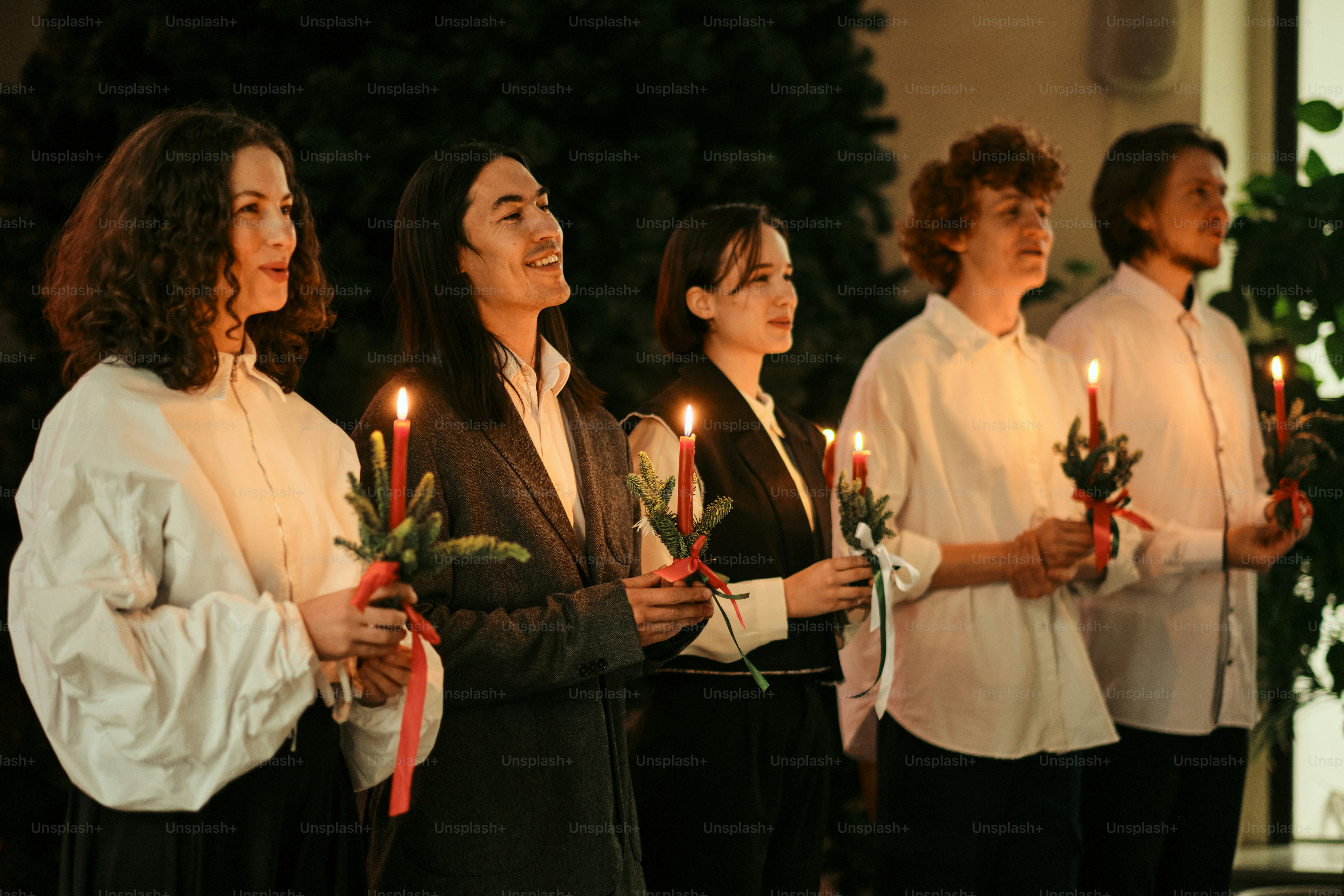 Um grupo de pessoas em pé um ao lado do outro segurando velas
