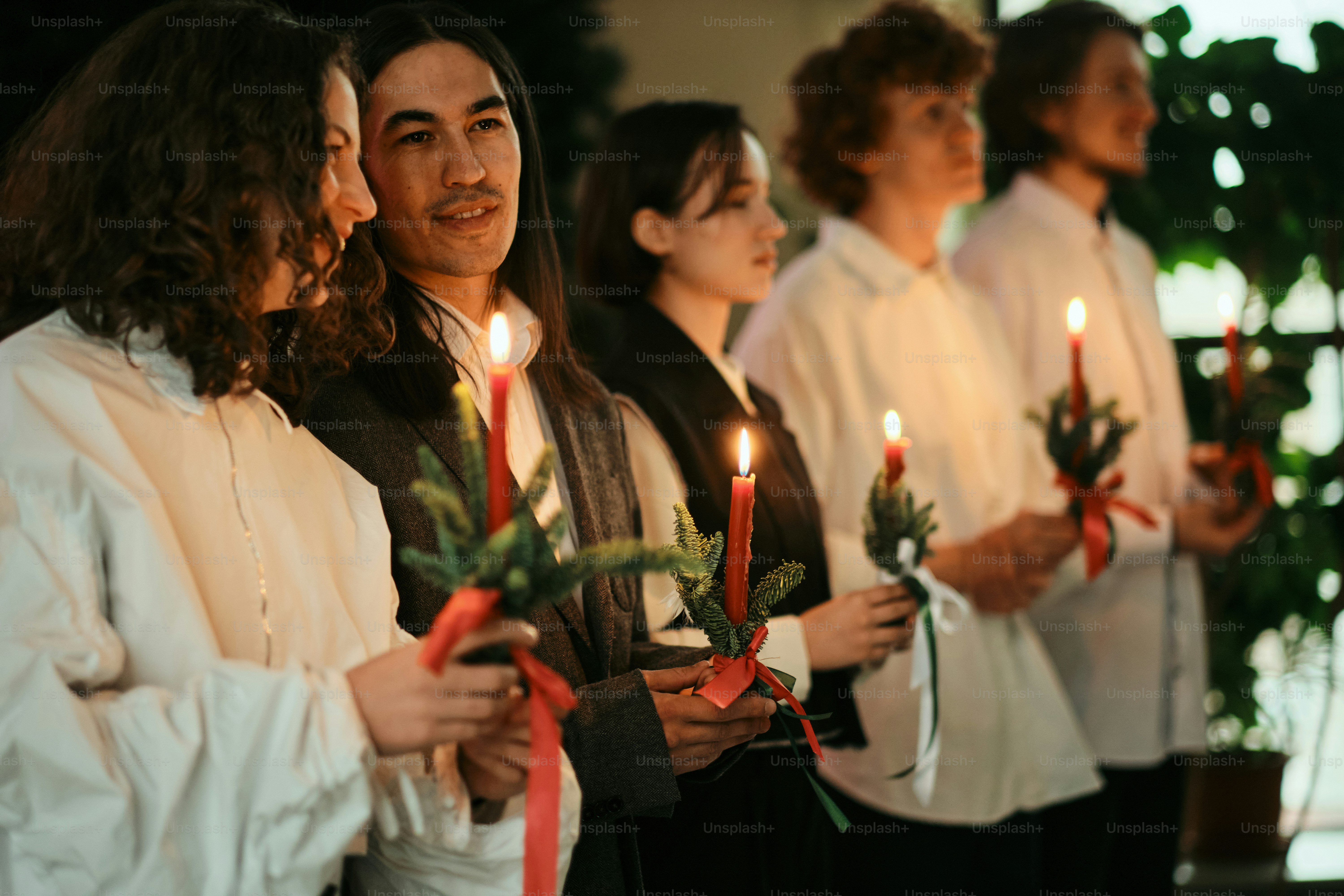 Um grupo de pessoas em pé um ao lado do outro segurando velas