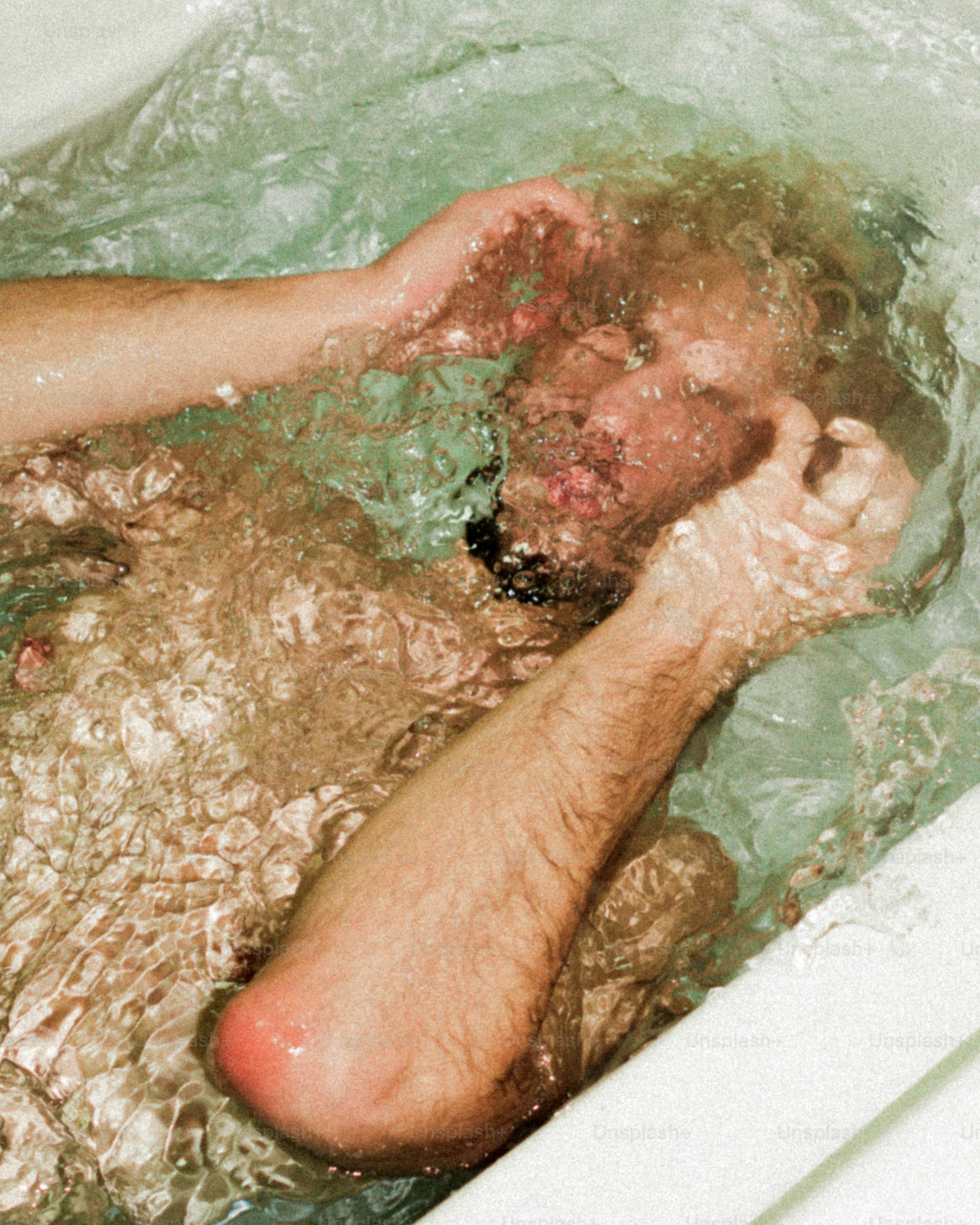 A man laying in a bathtub with his head in the water