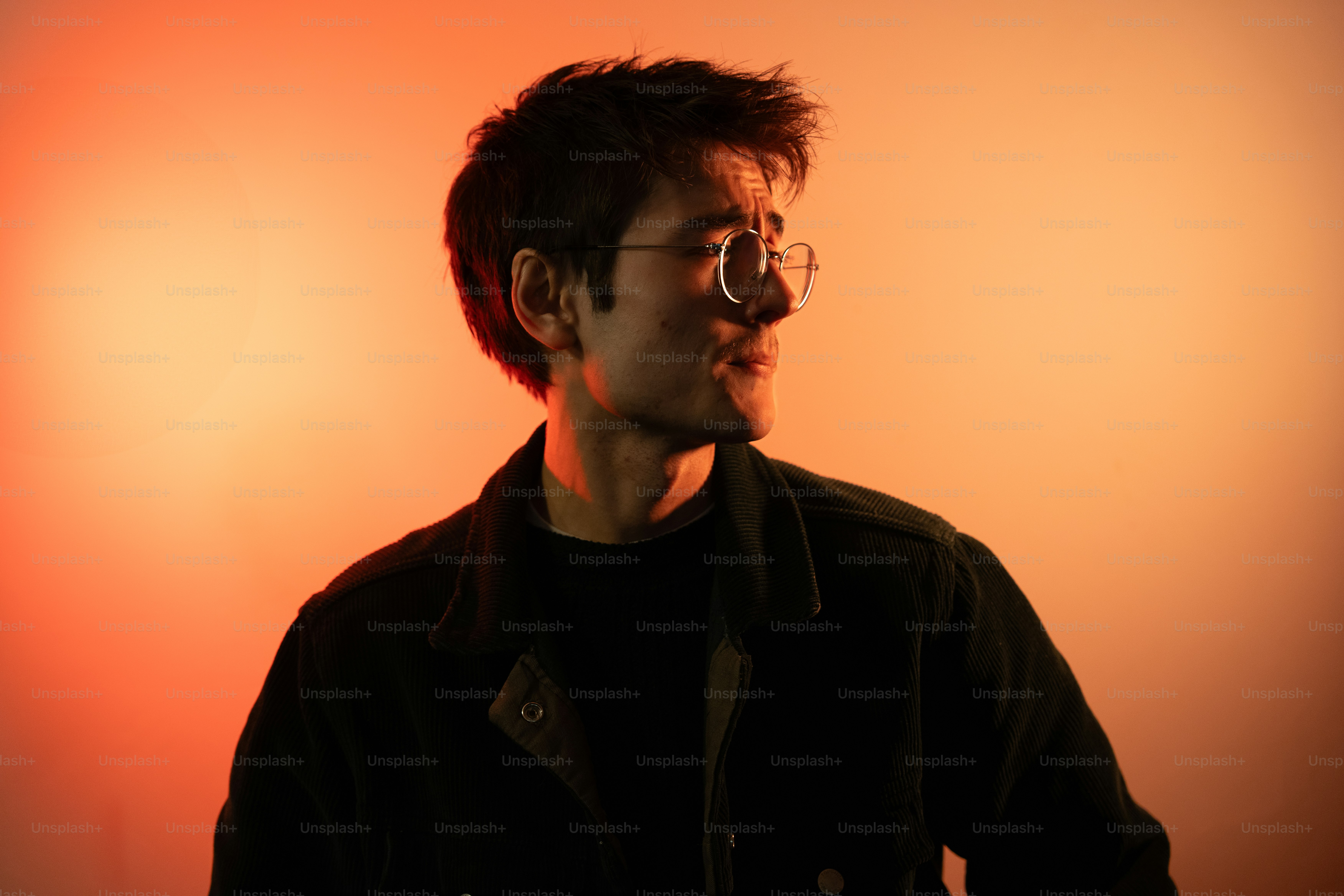 A man with glasses standing in front of a red light photo – Portrait ...