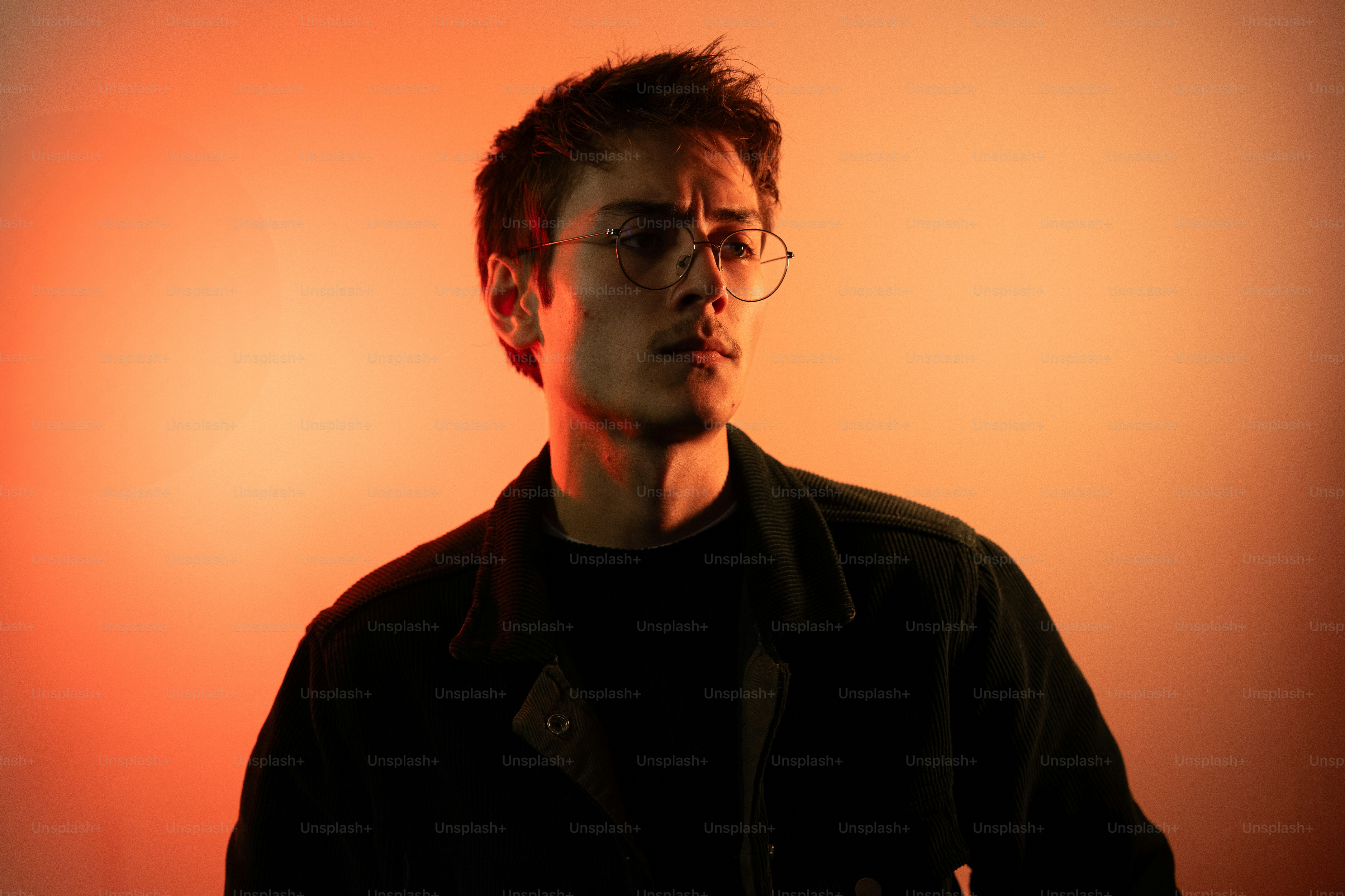 A man with glasses standing in front of a red wall photo – Portrait ...