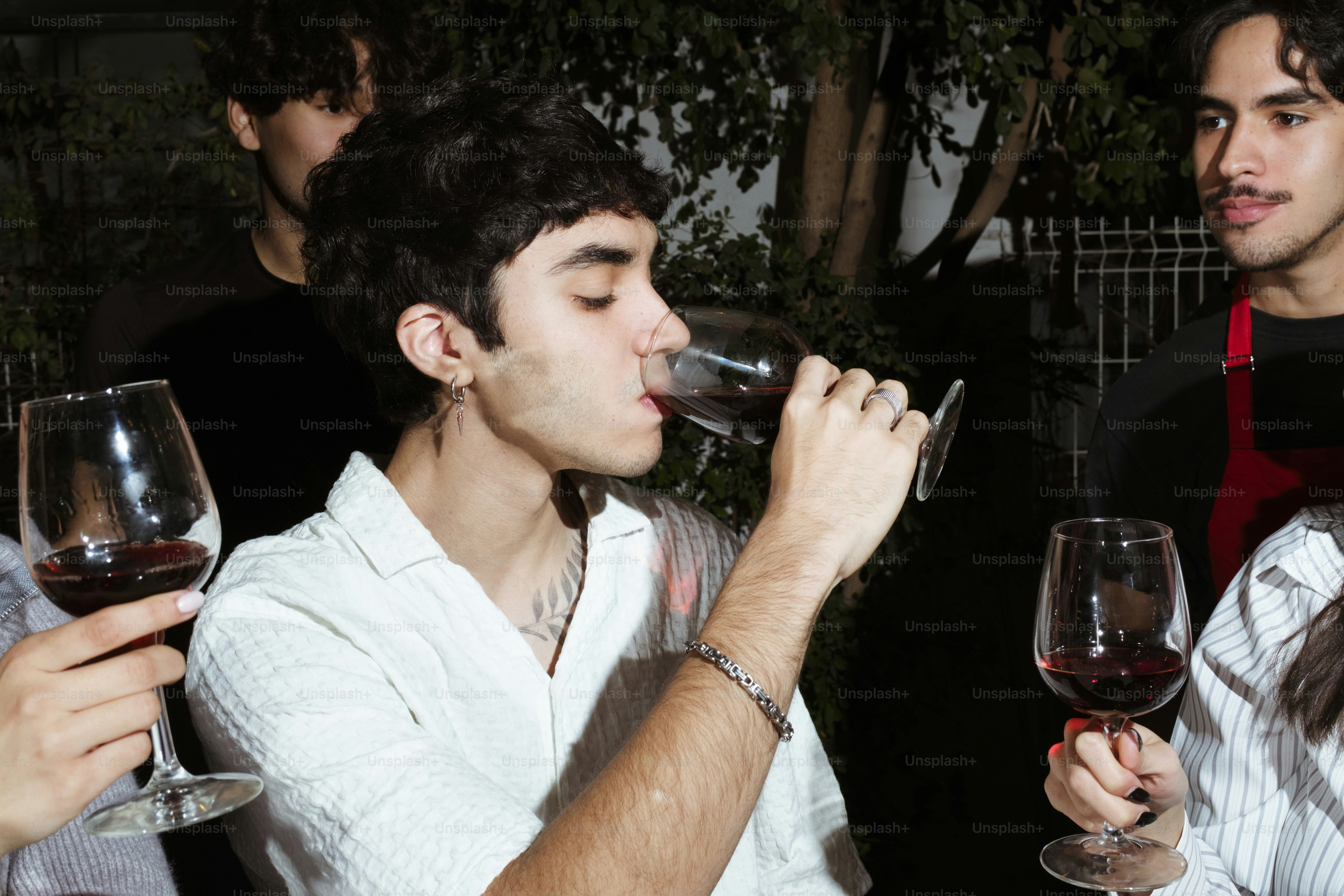 Two men and a woman drinking wine from wine glasses