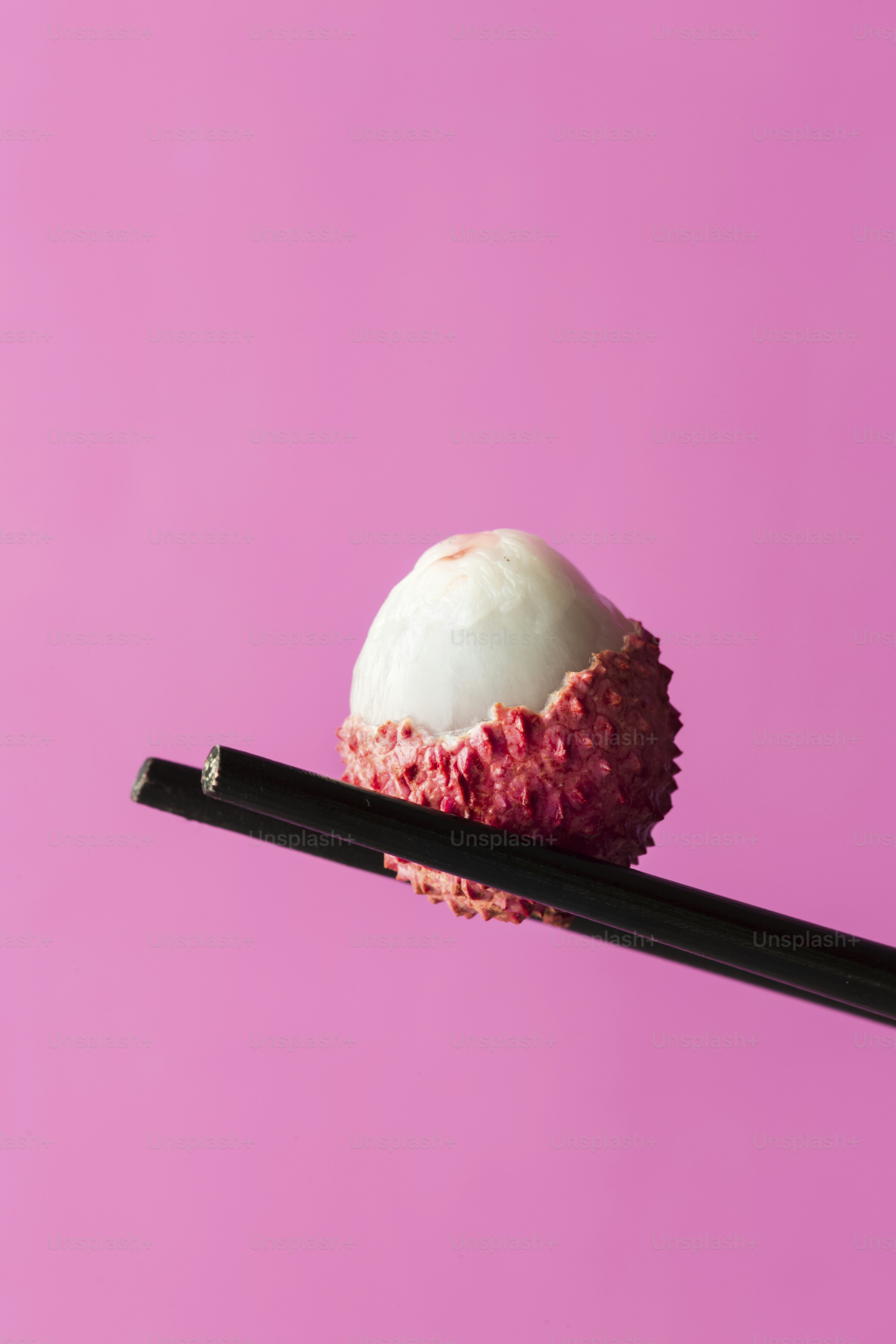 Un trozo de sushi sobre un palillo sobre un fondo rosa