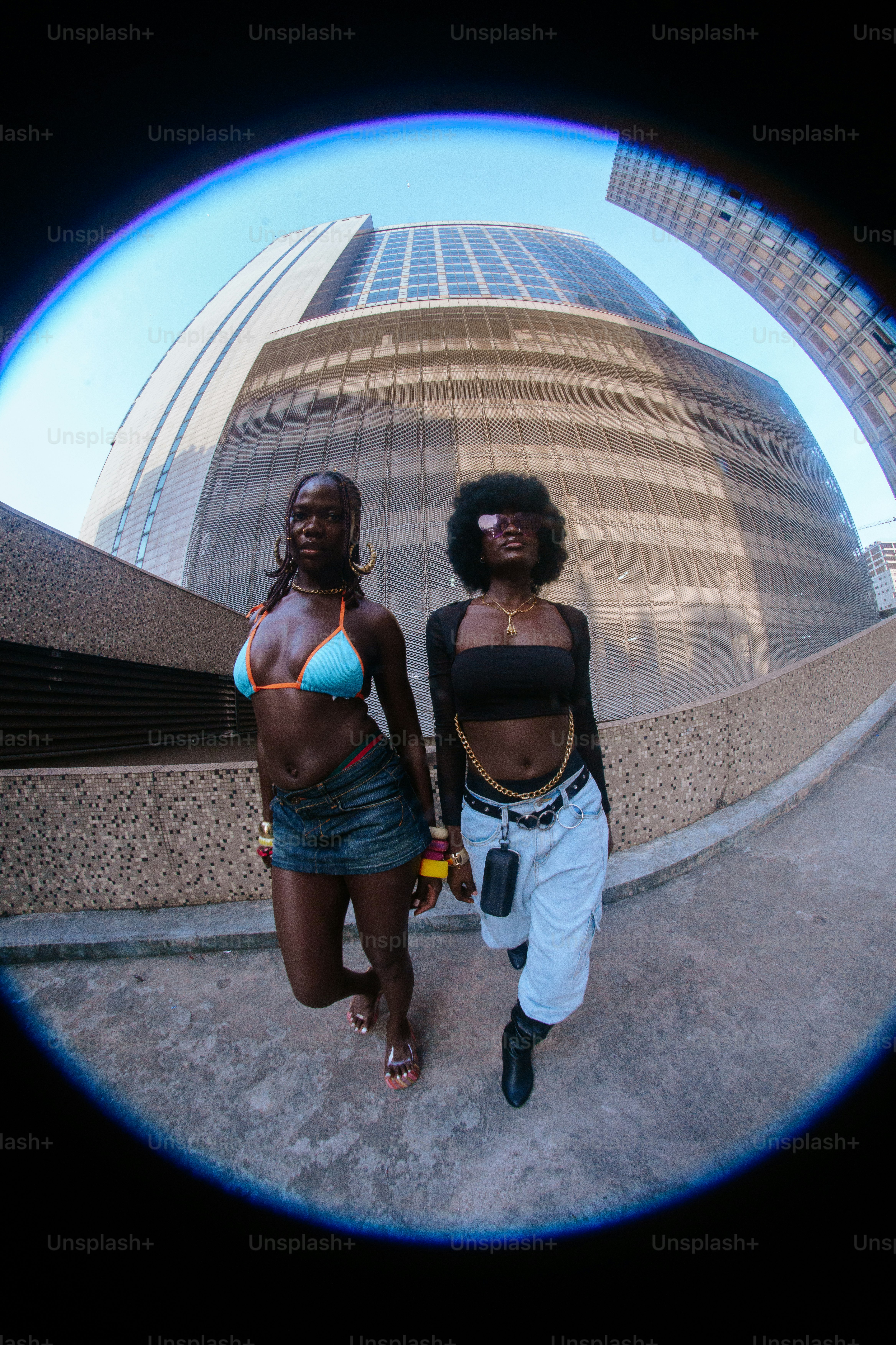 A couple of women walking down a street next to a tall building
