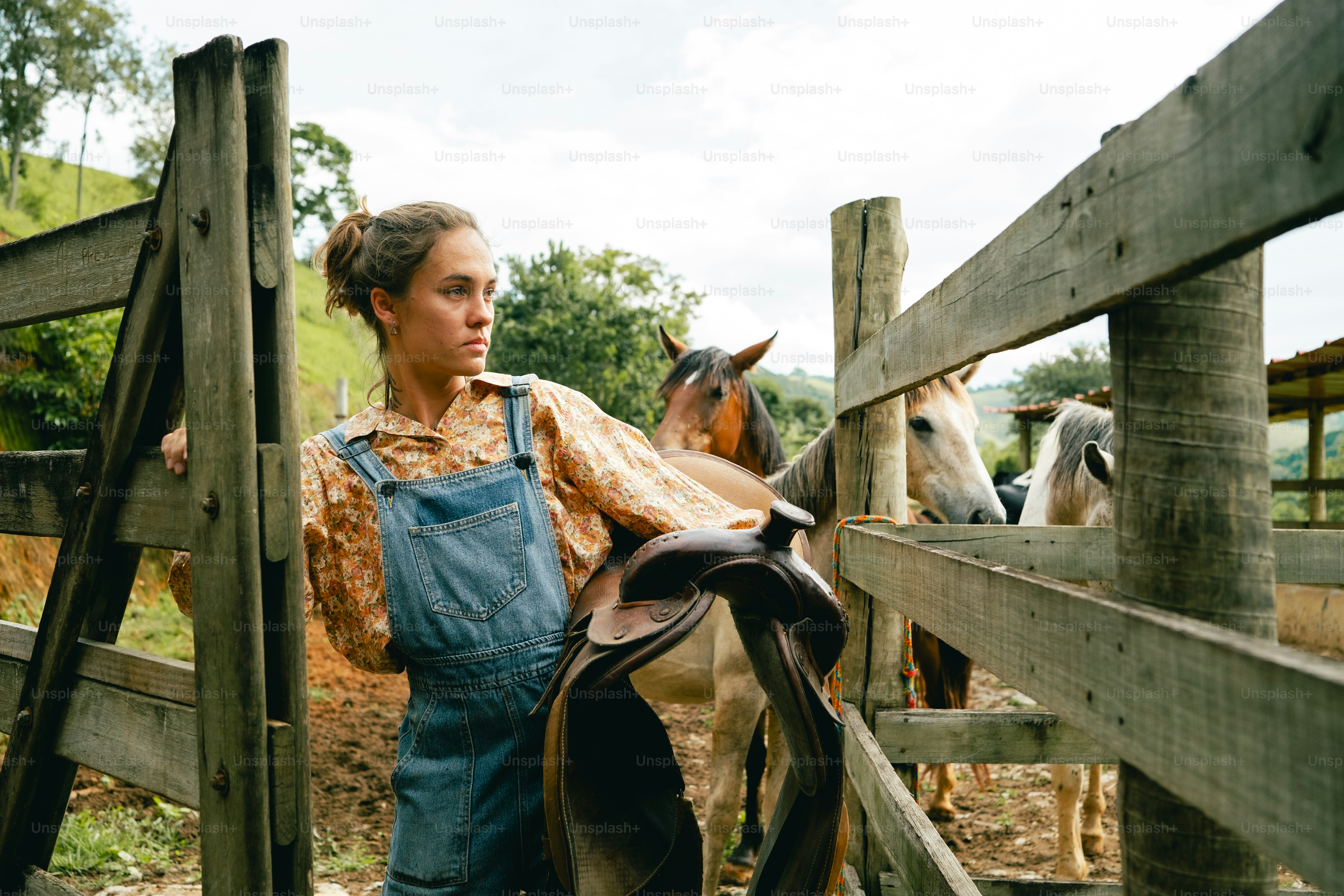 Eine Frau, die mit einem Pferd neben einem Zaun steht