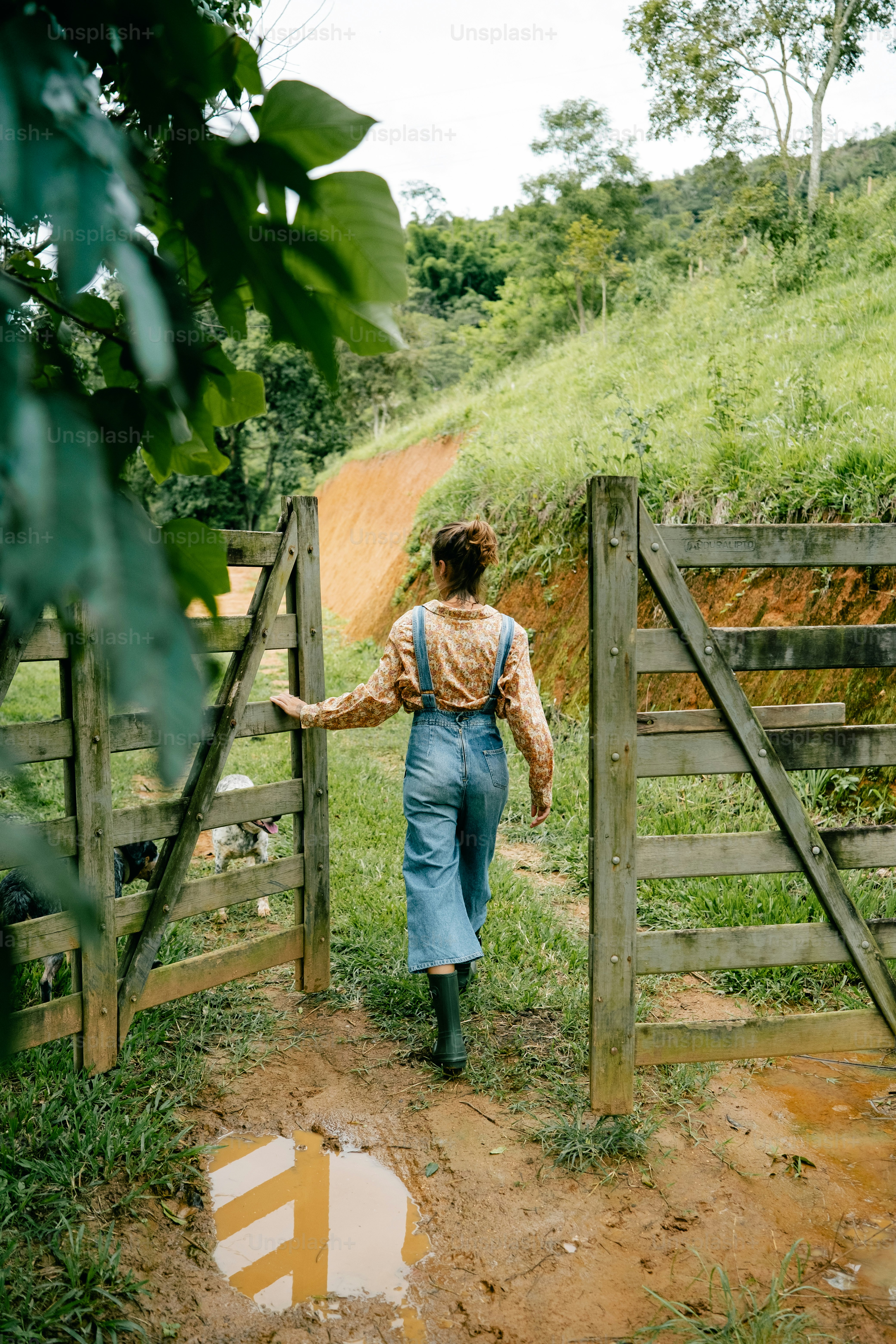 A woman in overalls walking up a dirt path