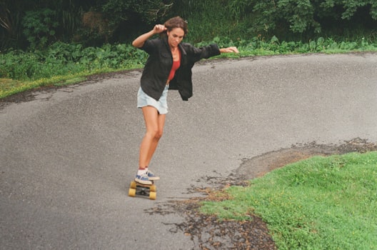 Woman riding a longboard down a curvy road through lush greenery