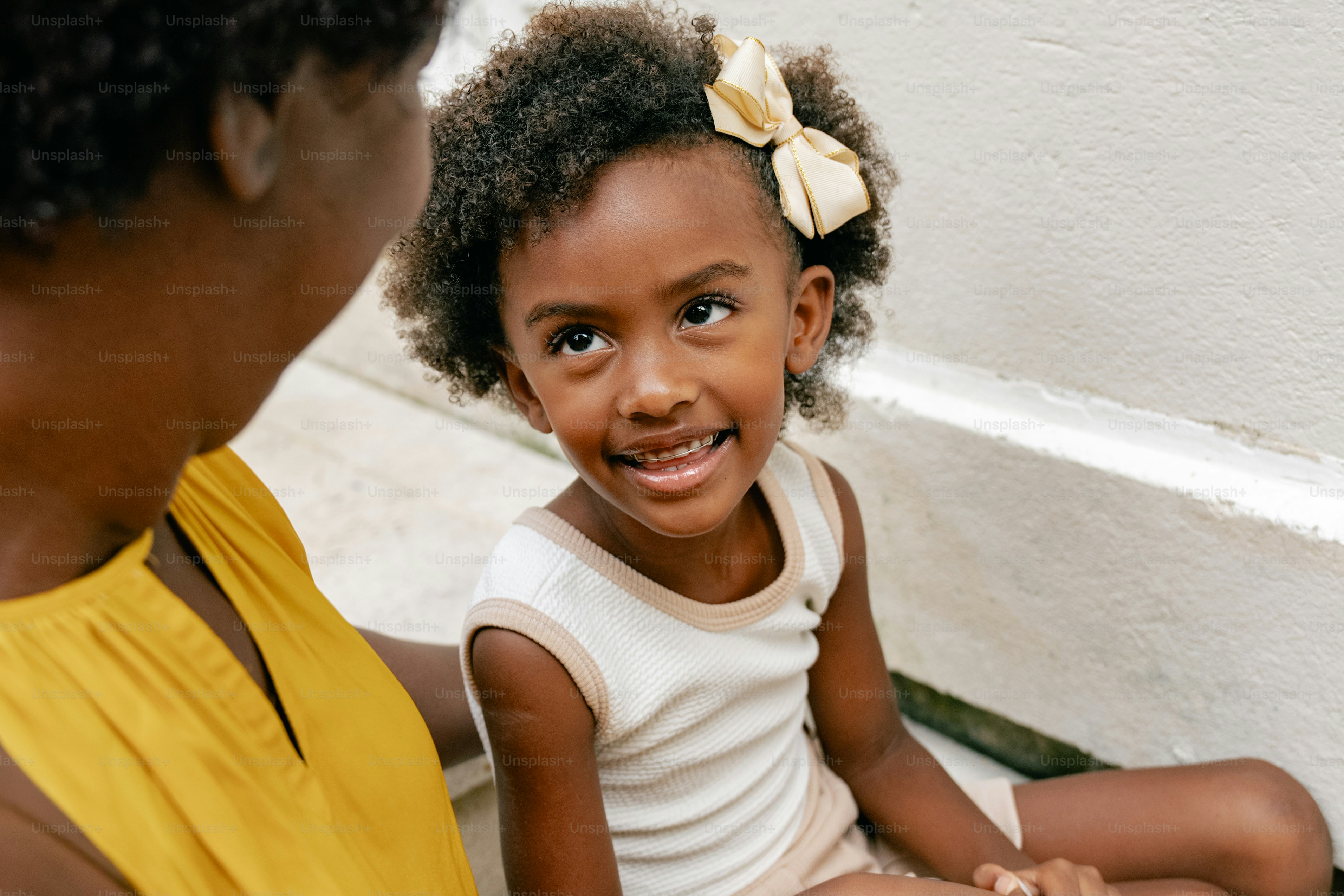 A little girl sitting on the ground next to a woman