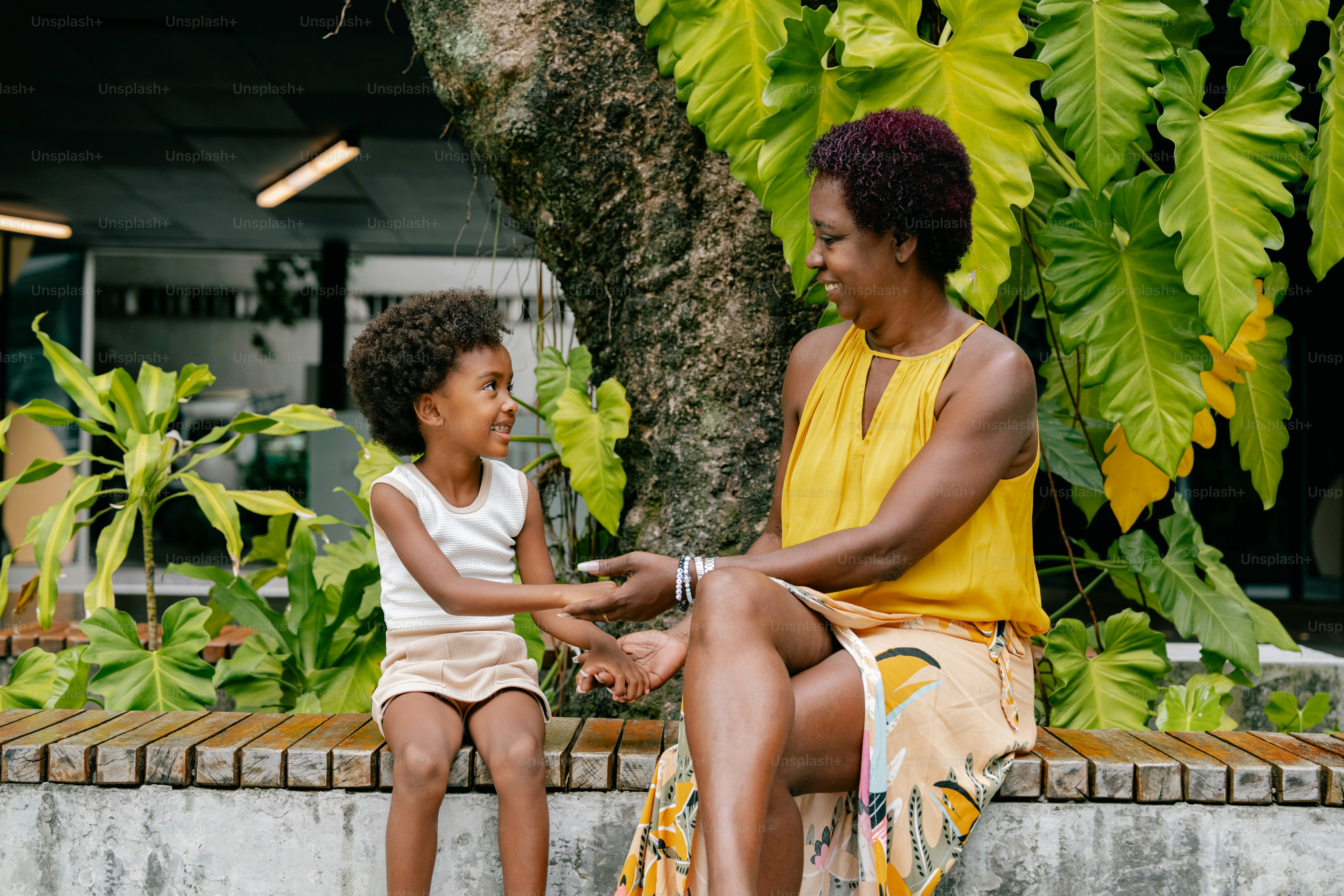 A woman sitting next to a little girl on a bench