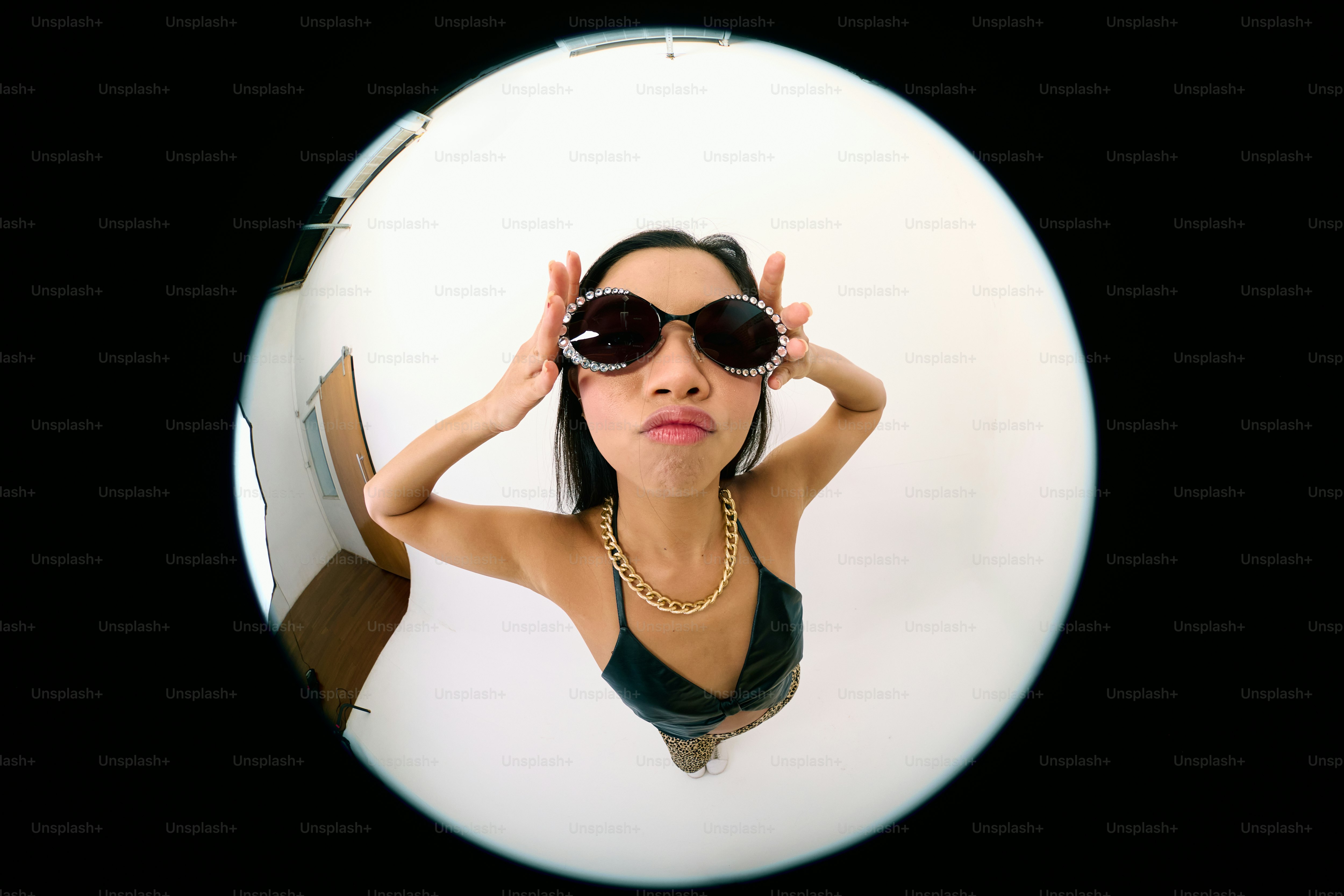A woman in a bathing suit and sunglasses looking into a mirror