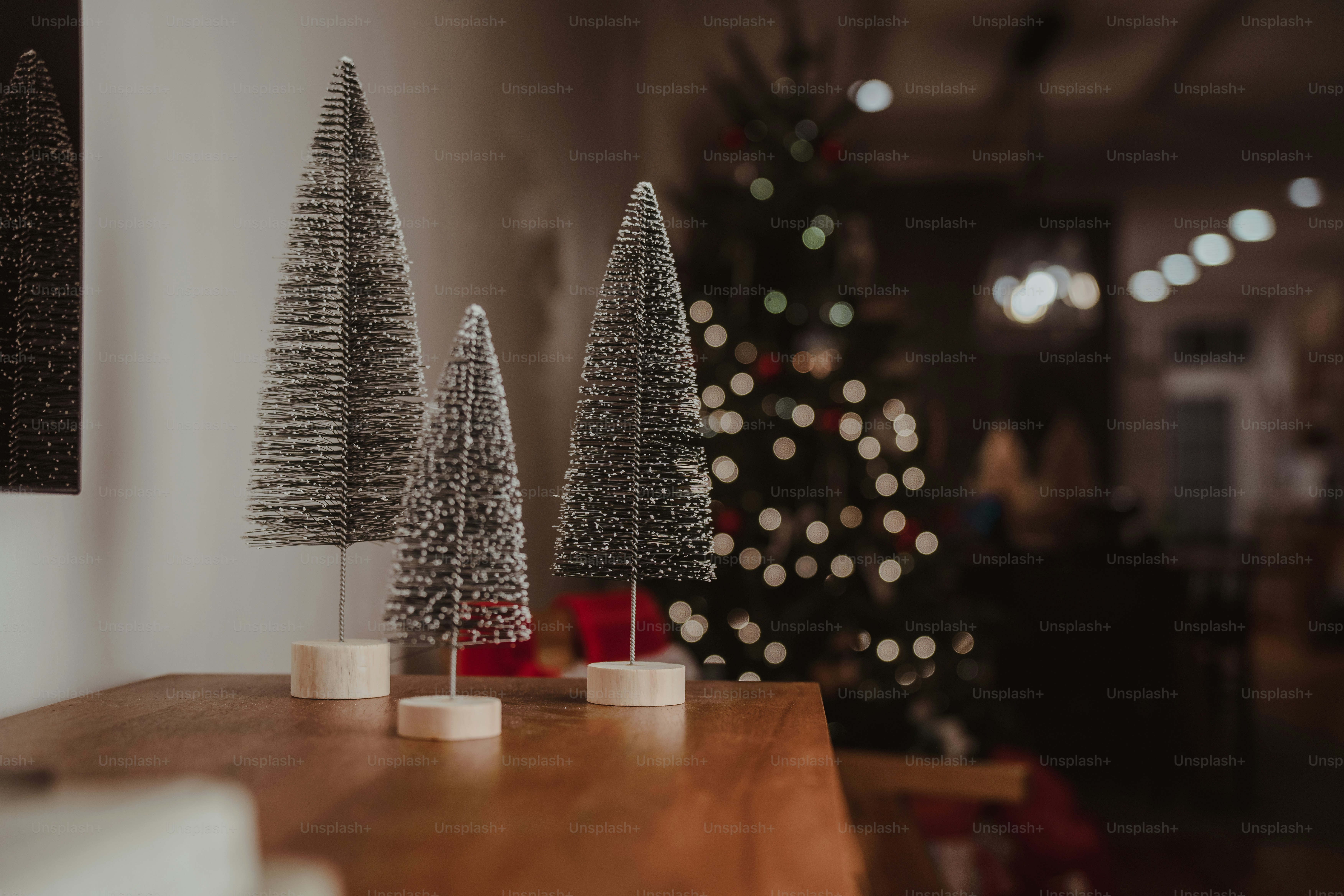 A wooden table topped with christmas trees next to a christmas tree