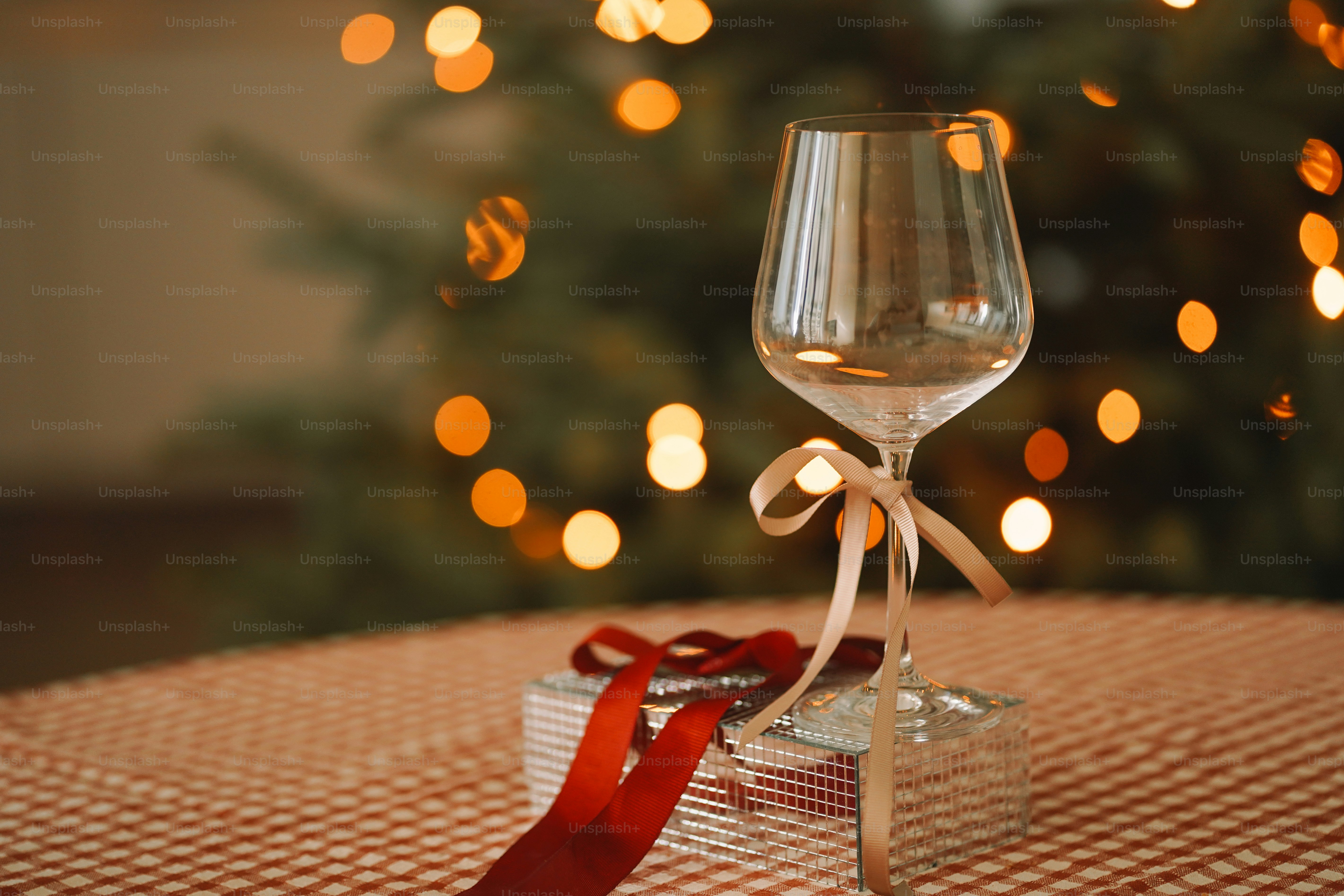 A wine glass sitting on a table next to a christmas tree