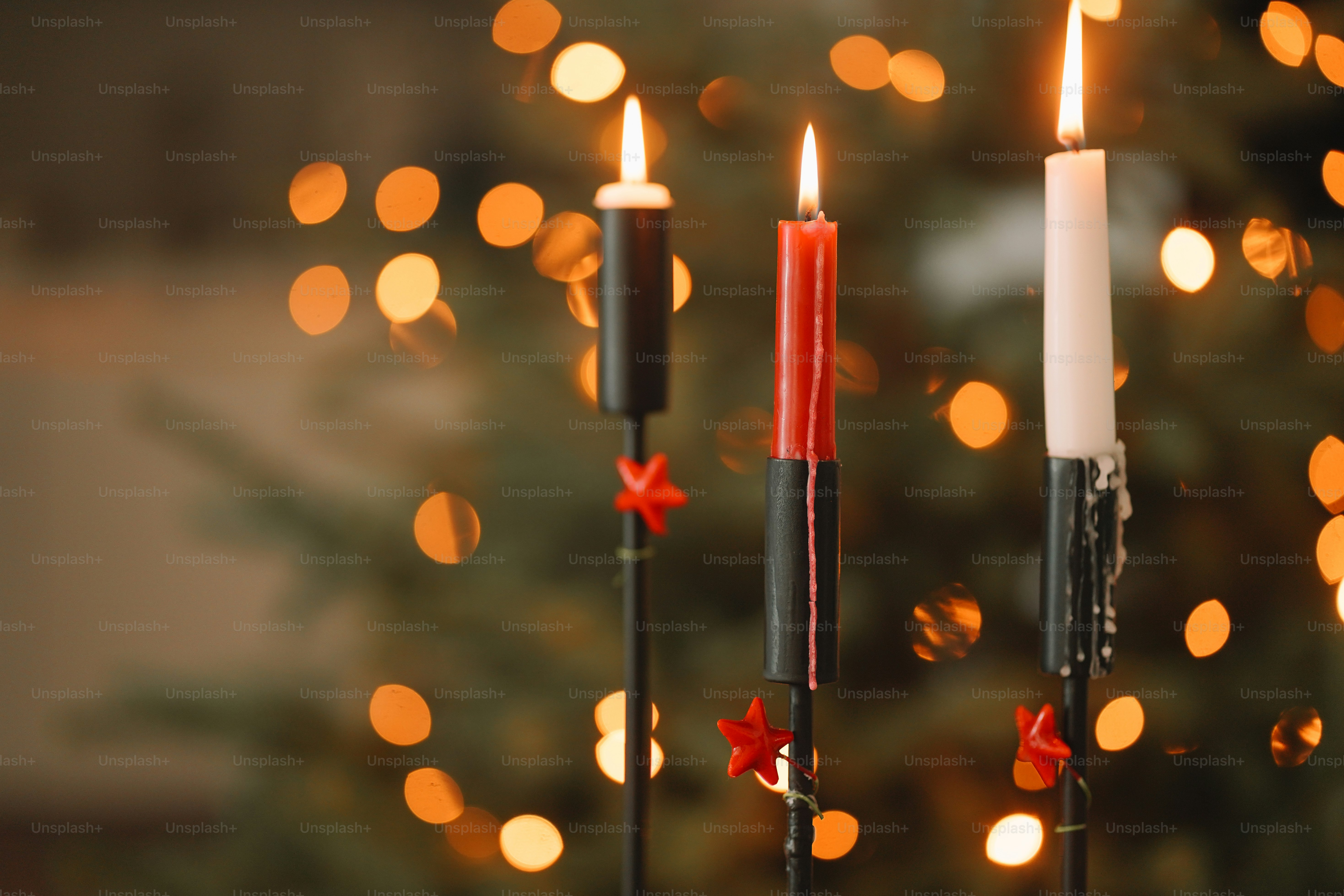 A group of three candles sitting next to a christmas tree