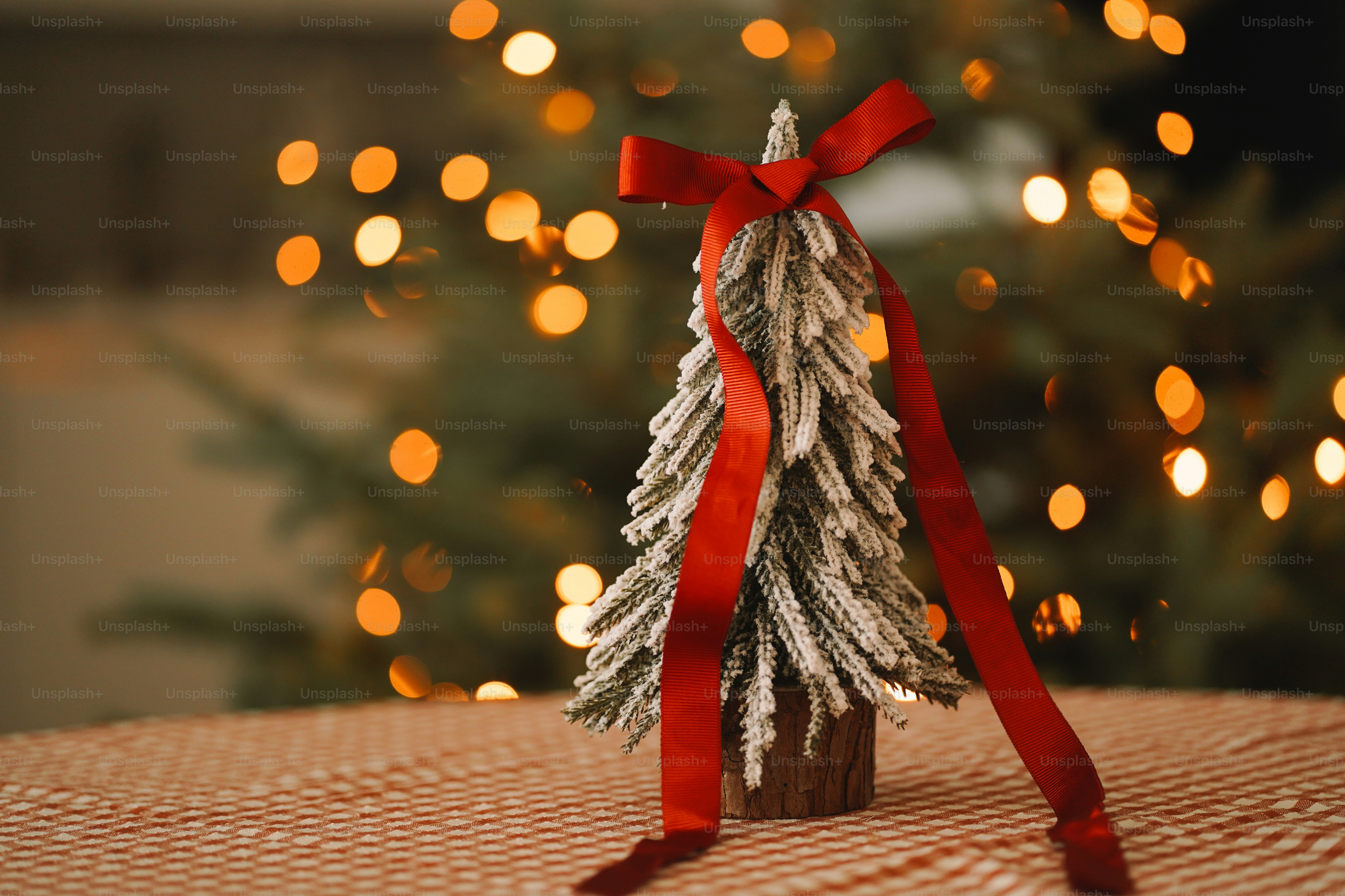 A small christmas tree on a table with a red ribbon