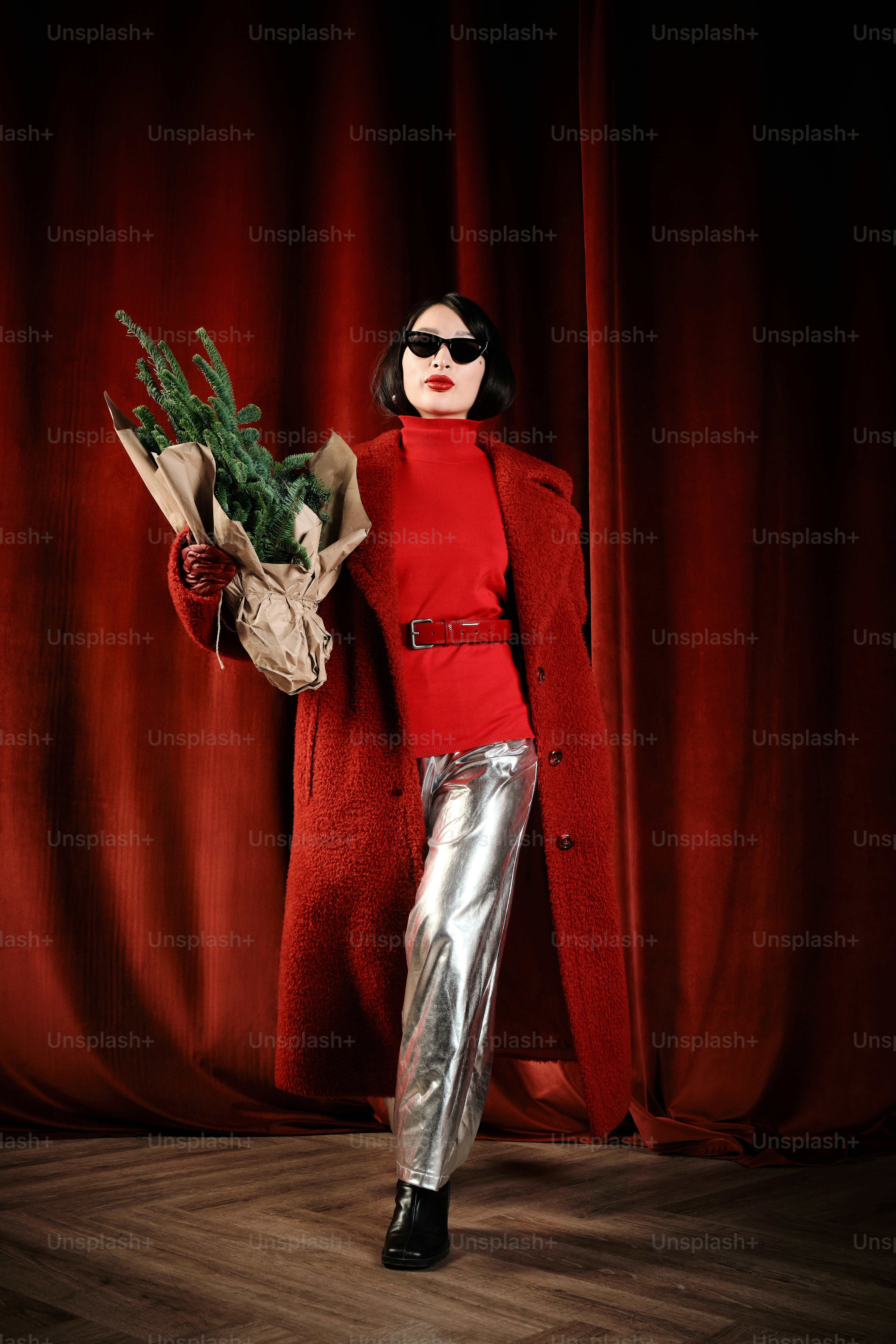 A woman holding a bouquet of flowers in front of a red curtain photo ...