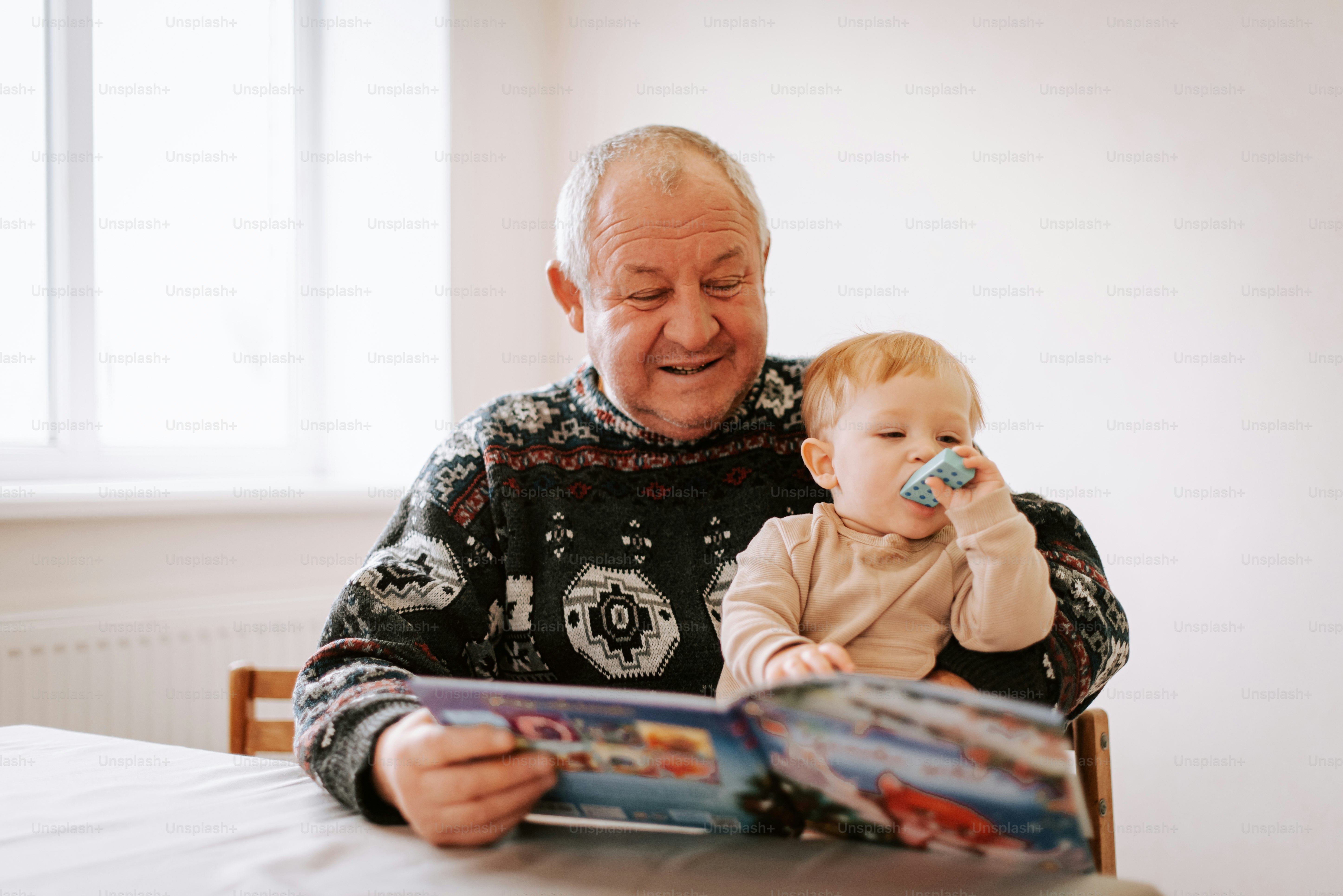 An older man sitting at a table with a baby