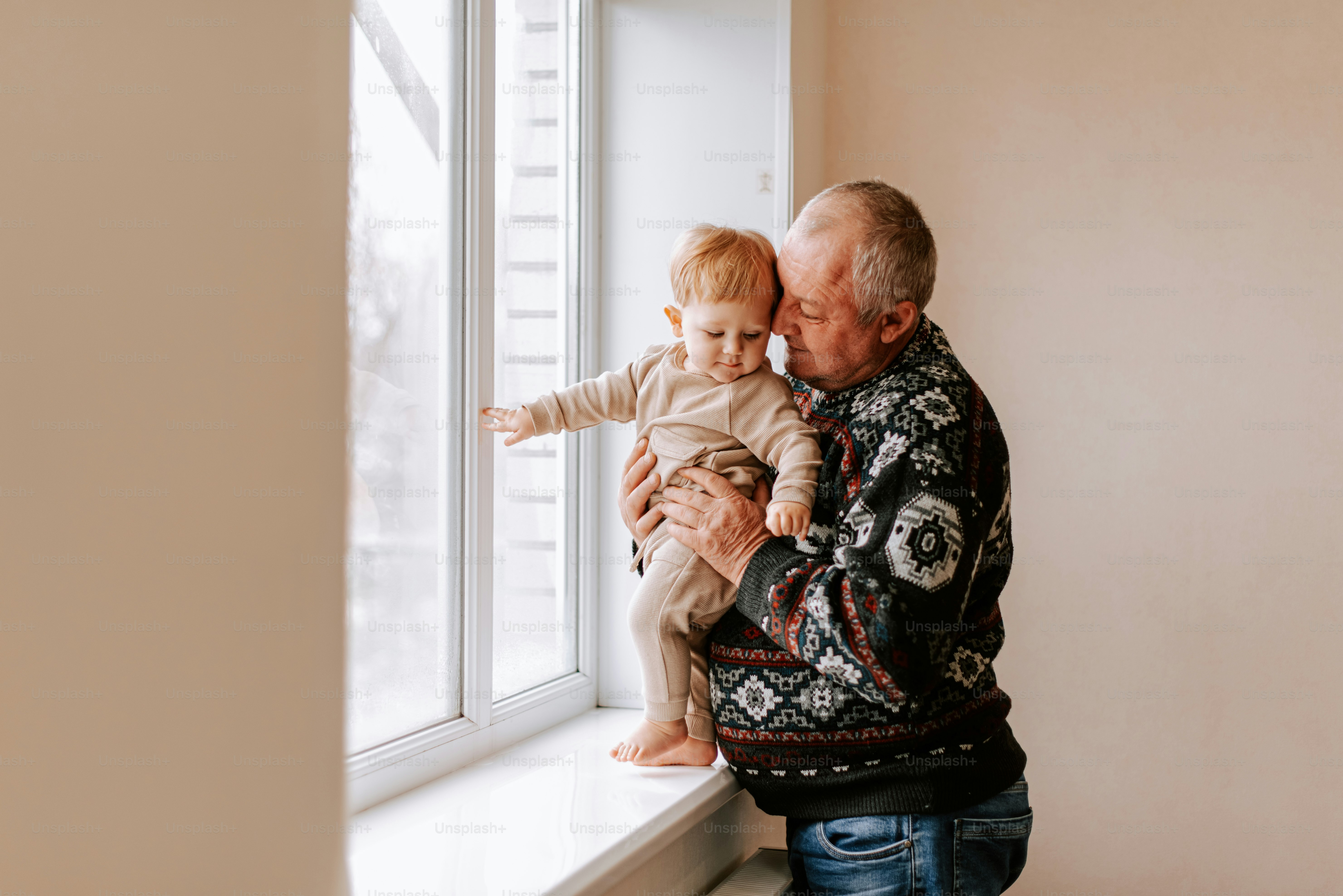 A man holding a baby looking out a window