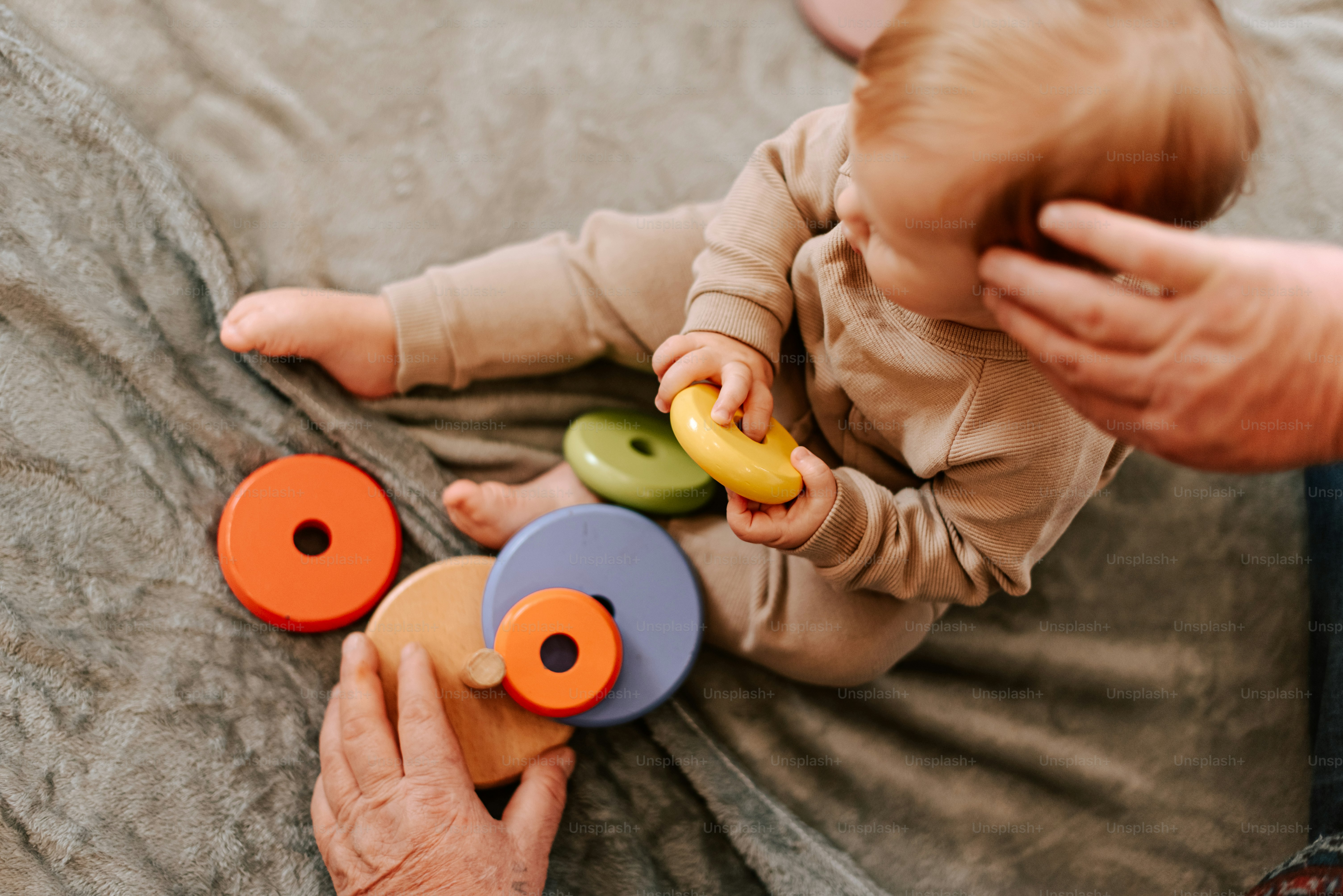 A baby is playing with a toy on a blanket
