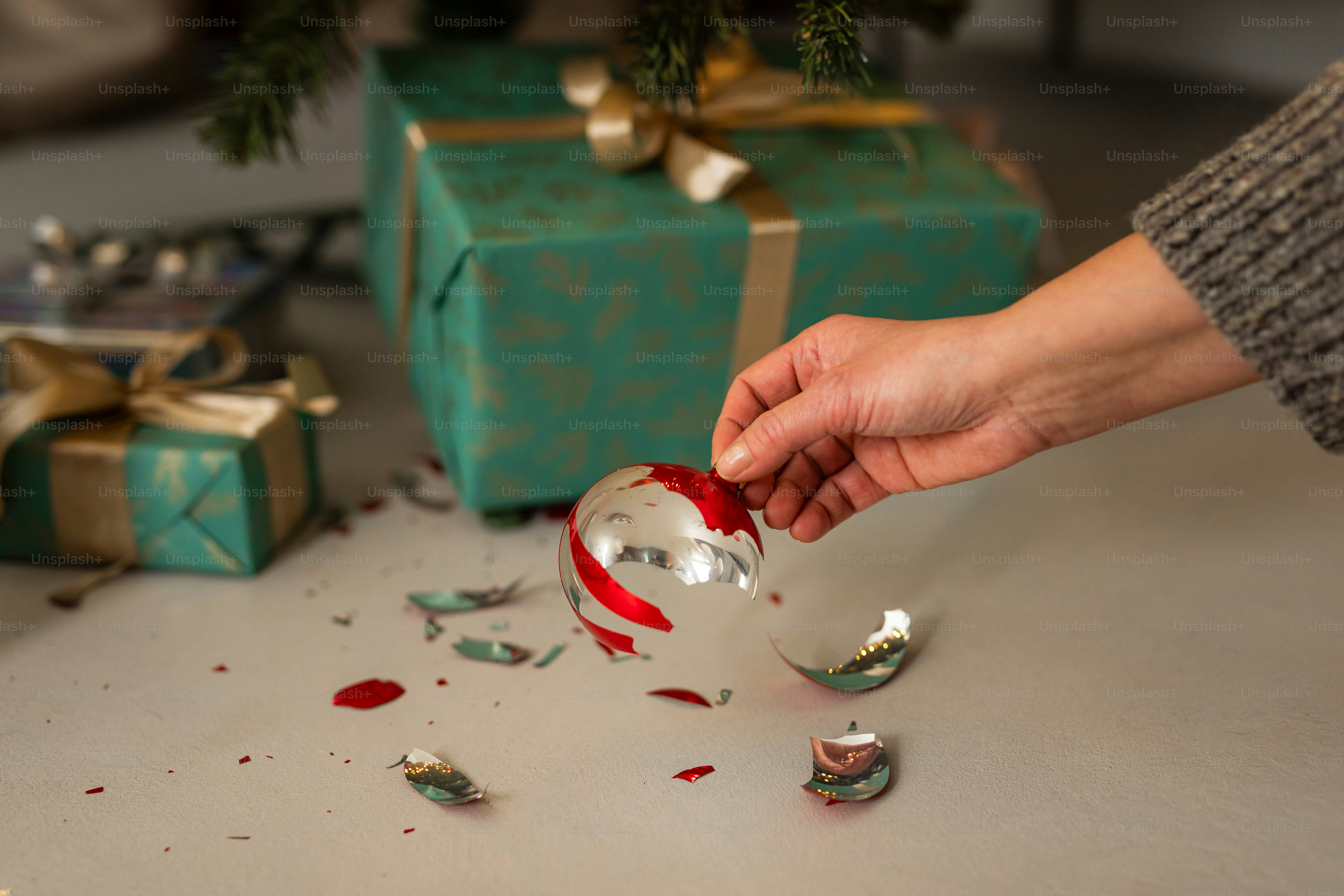 A person opening a christmas ornament with a christmas tree in the background