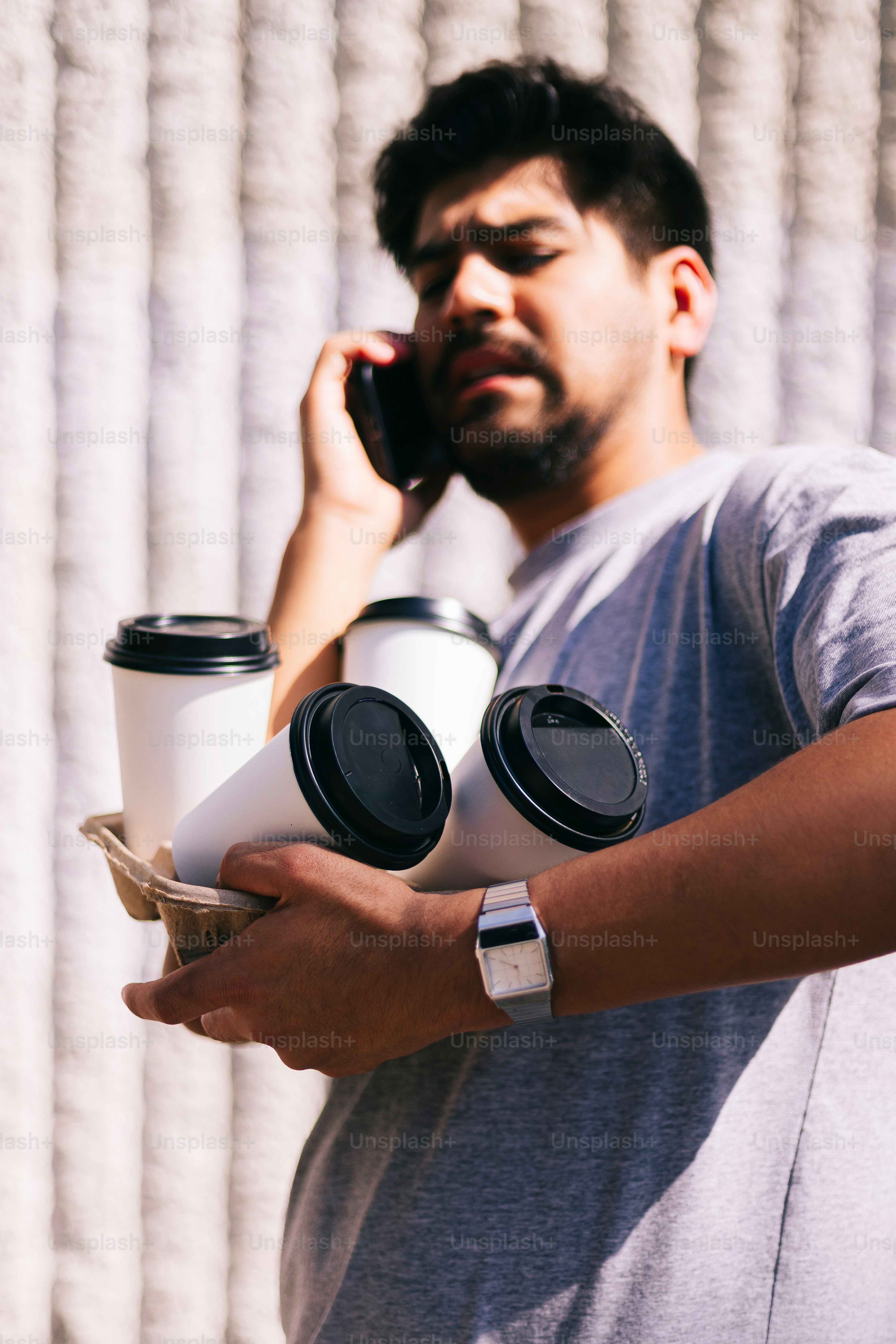 A man talking on a cell phone while holding a cup of coffee