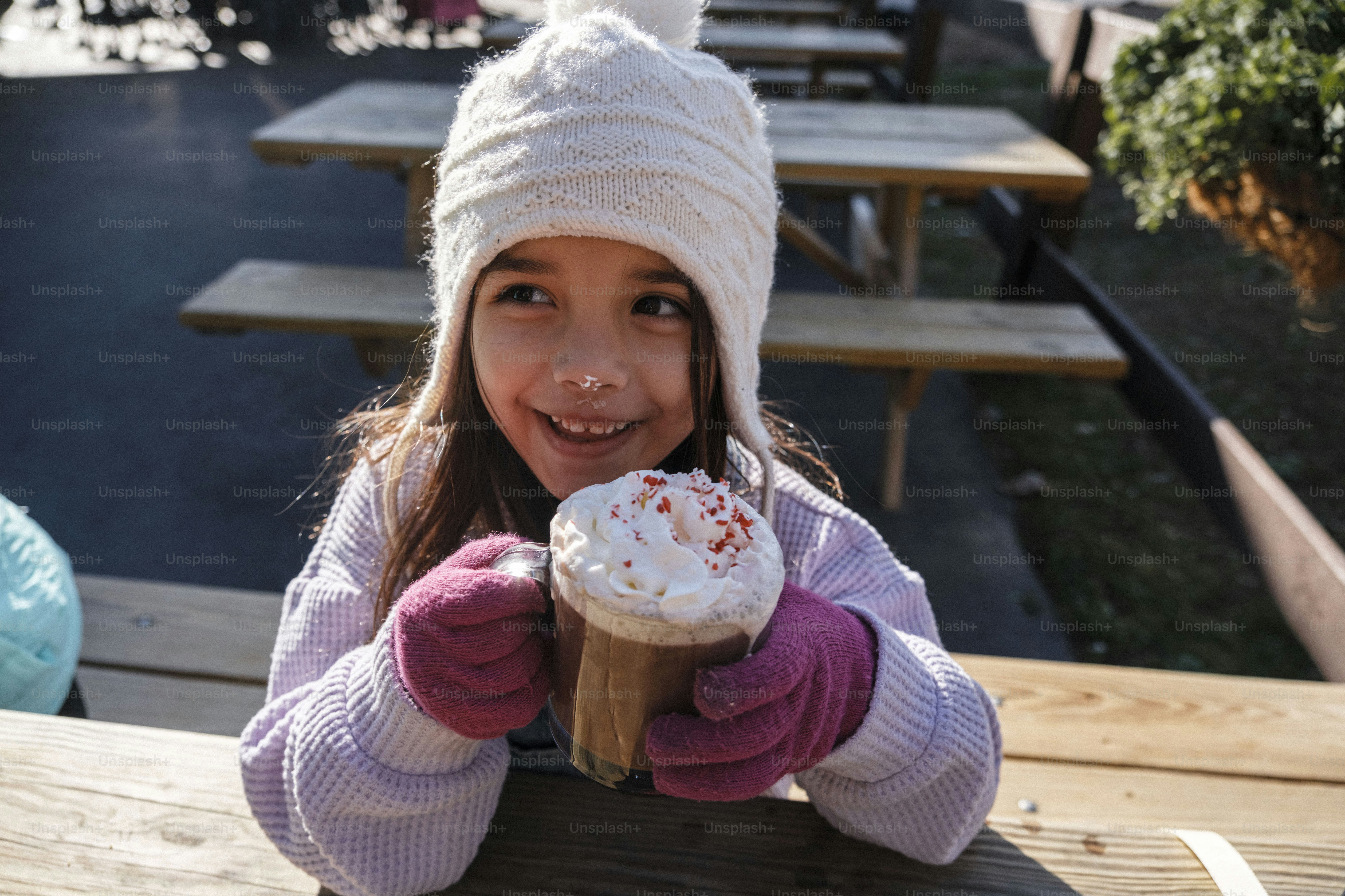 A little girl holding a cupcake in front of her face