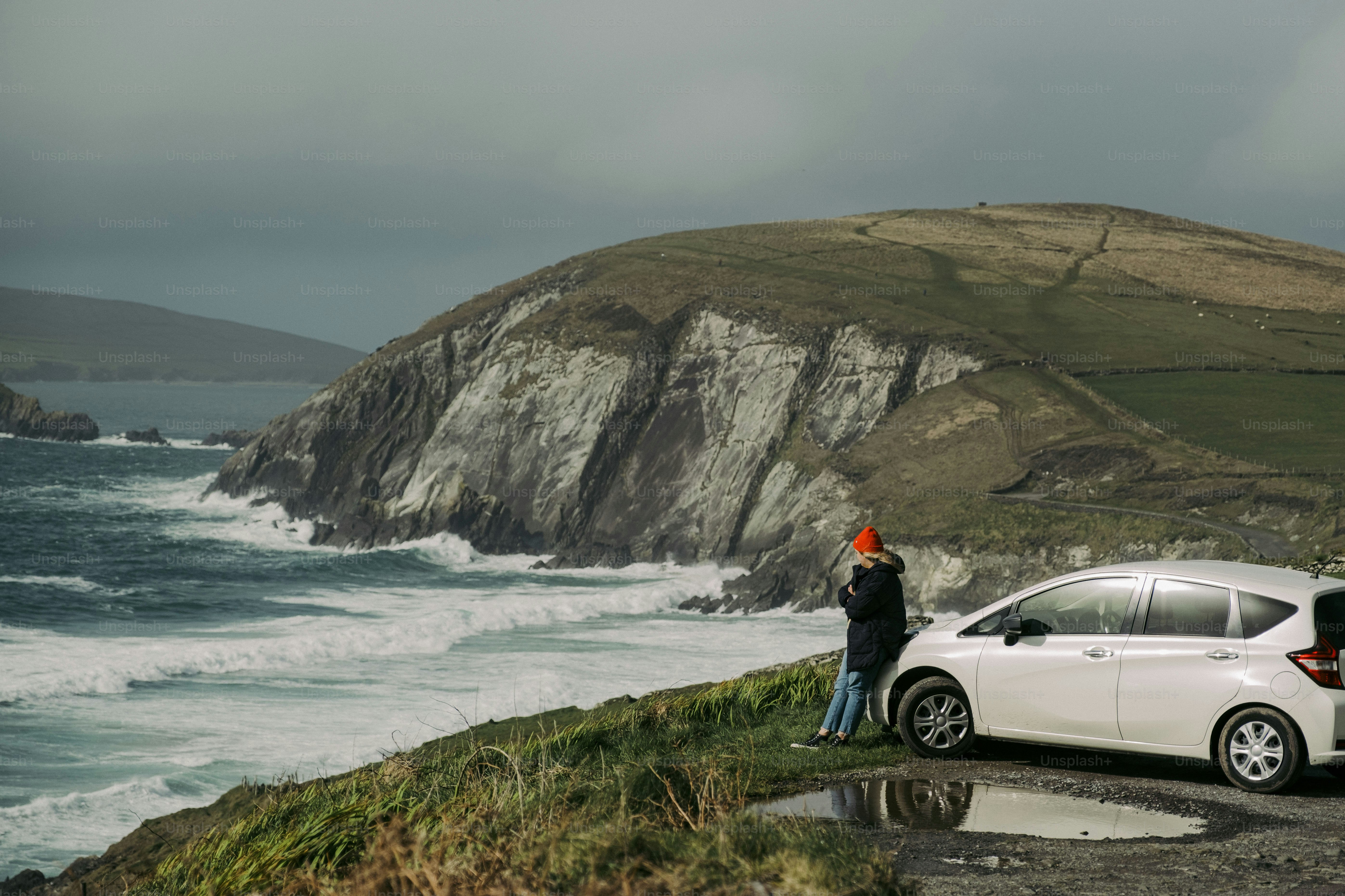 A white car parked on the side of a road next to the ocean