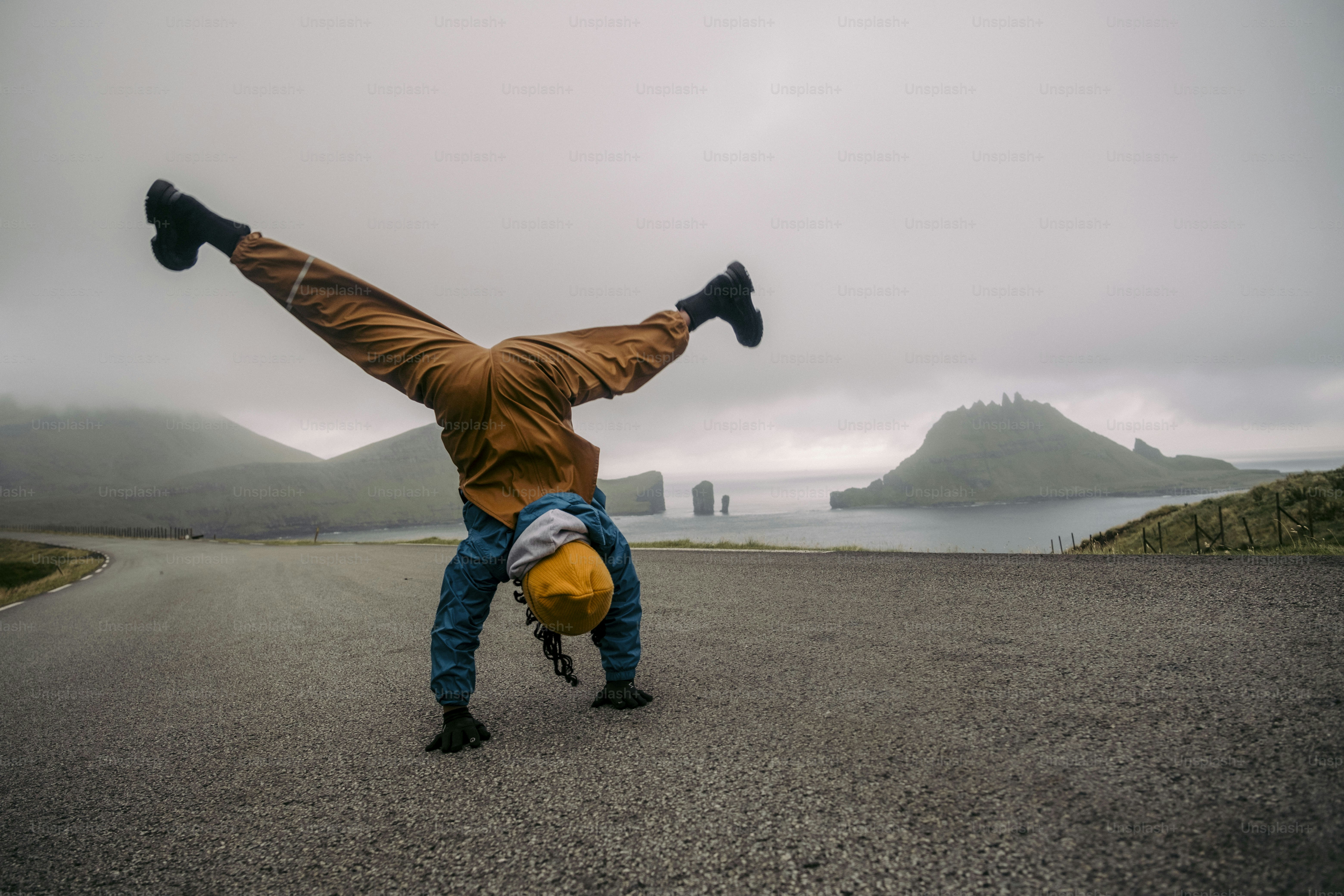 A man doing a handstand on the side of a road