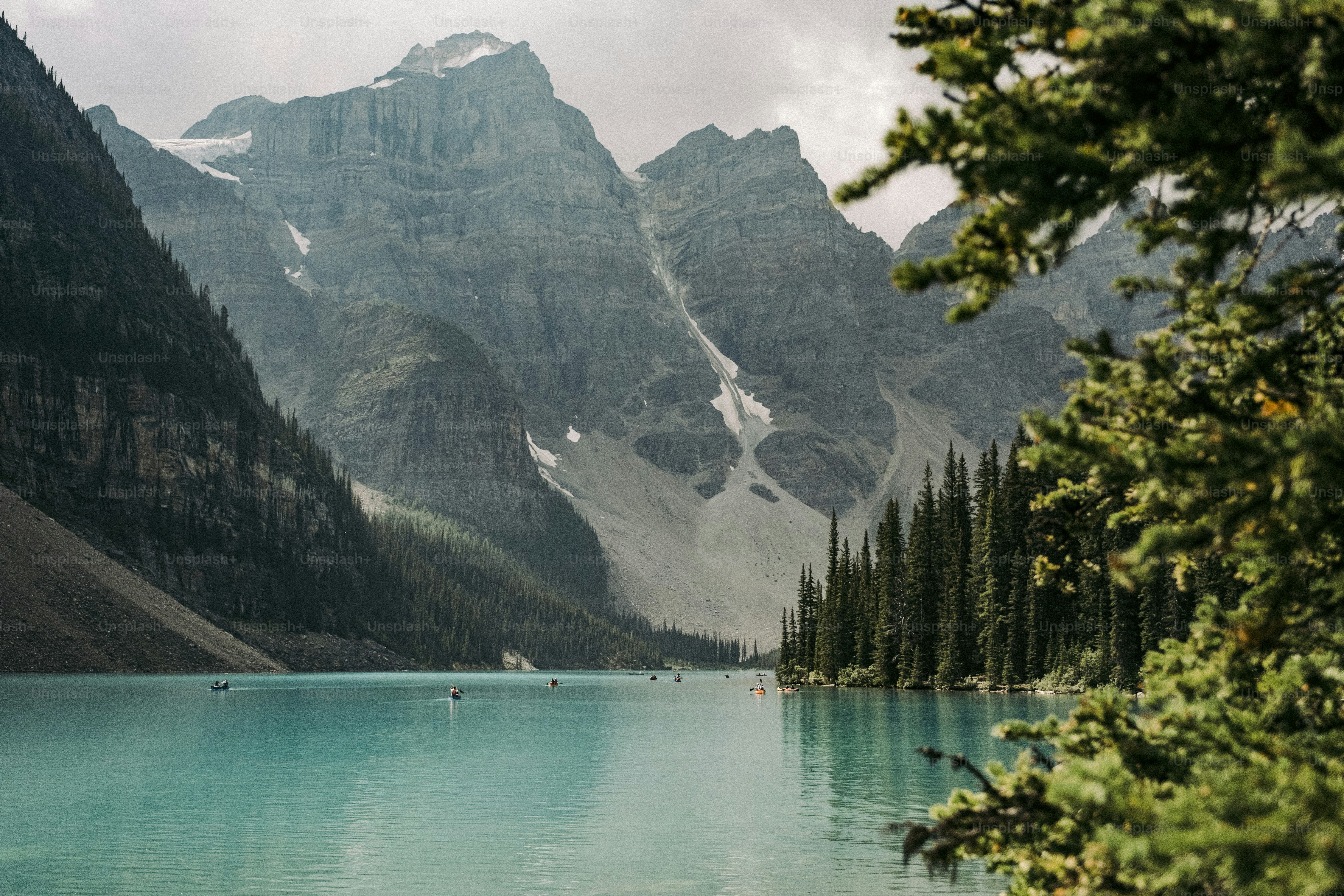A lake surrounded by mountains and trees on a cloudy day