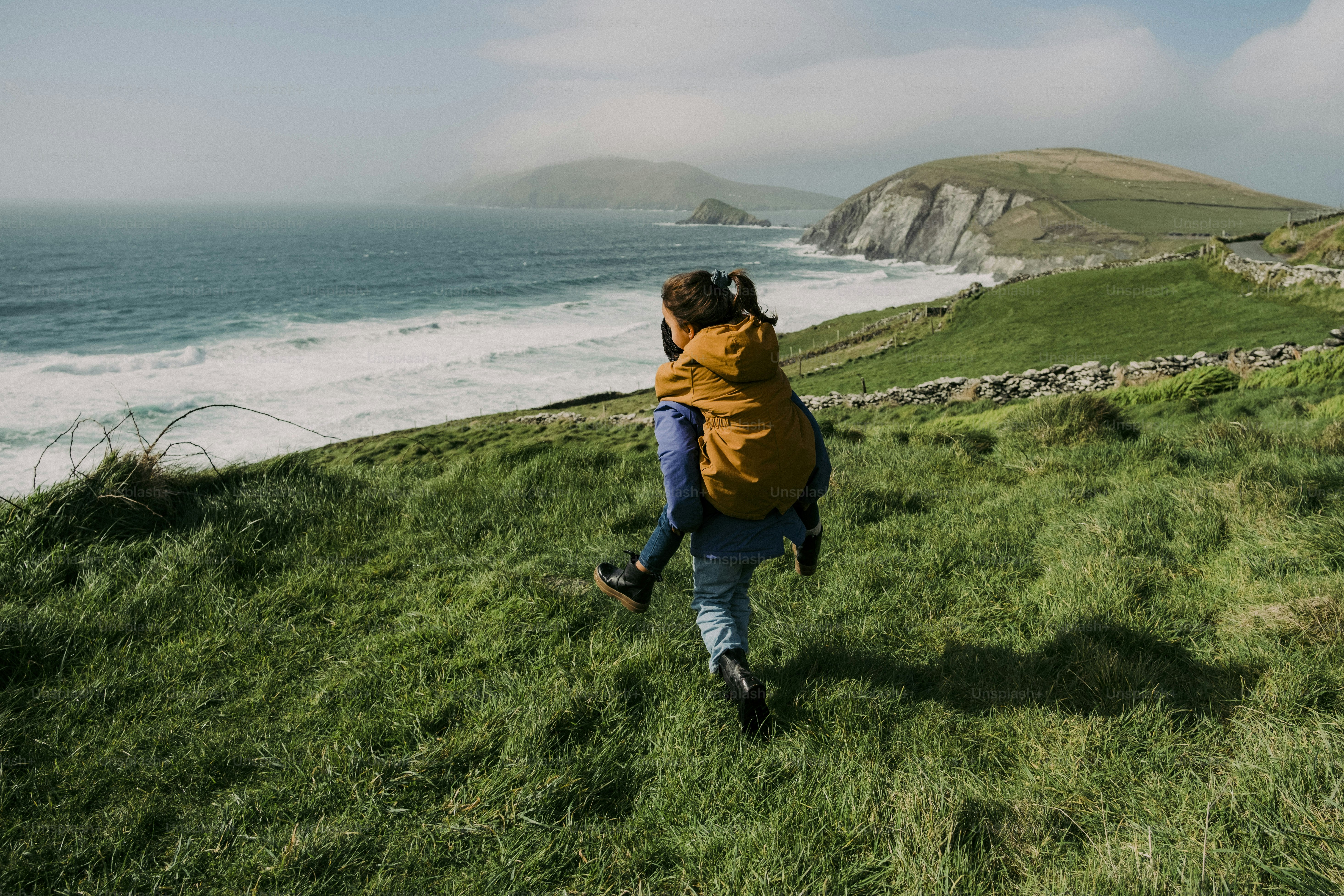 A person walking up a hill near the ocean
