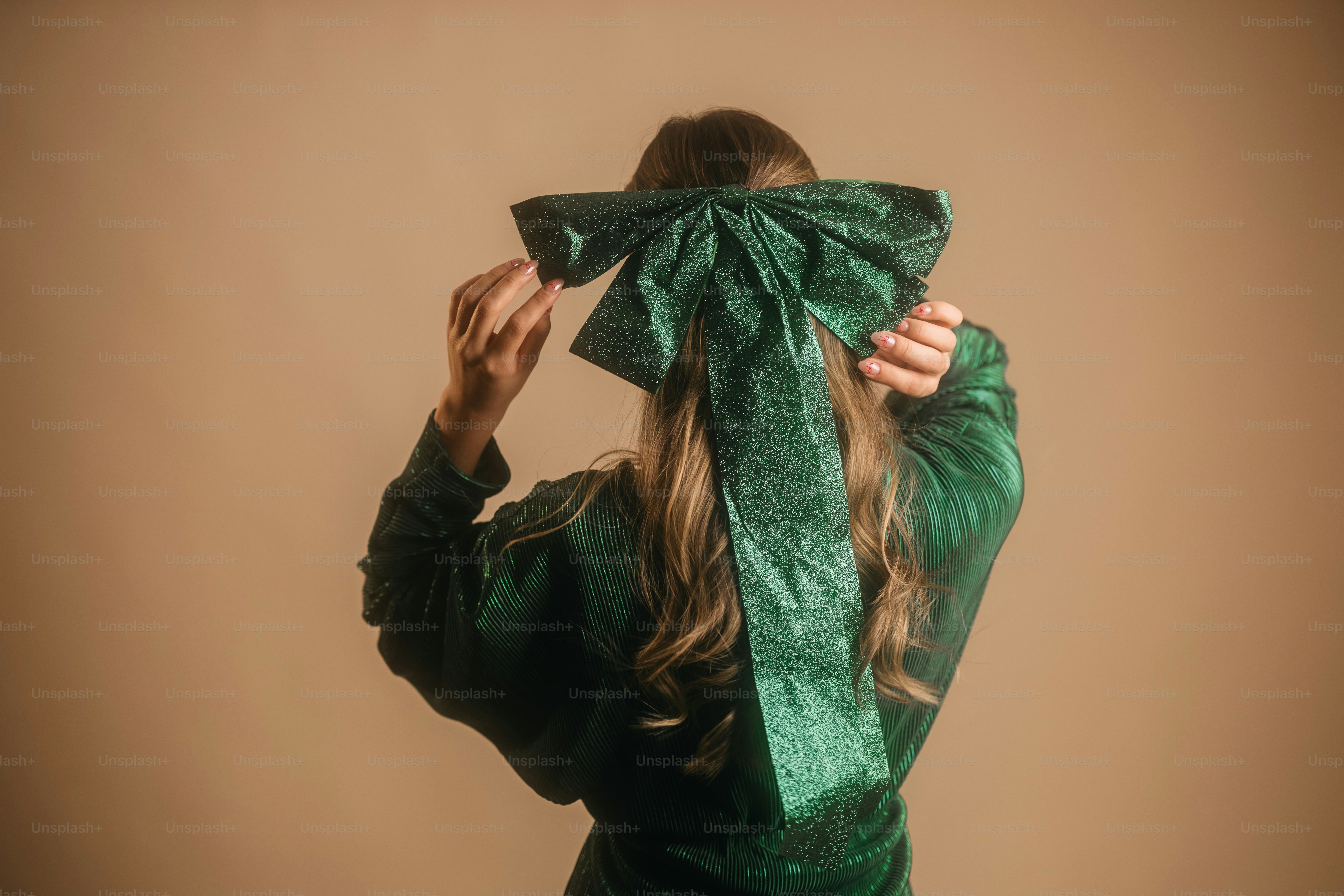 A woman in a green dress covering her face with a green bow