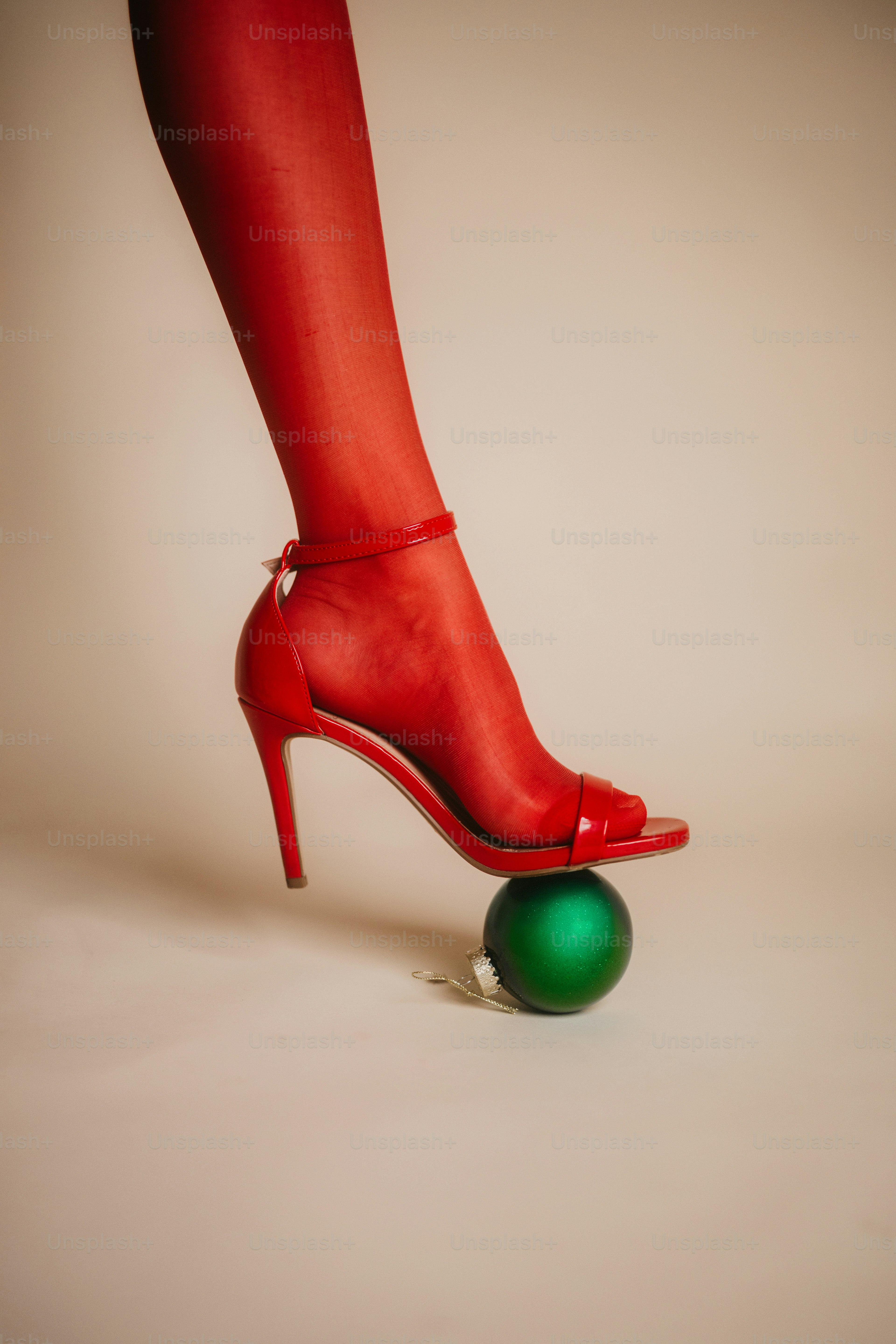 A red high heeled shoe with a green ball