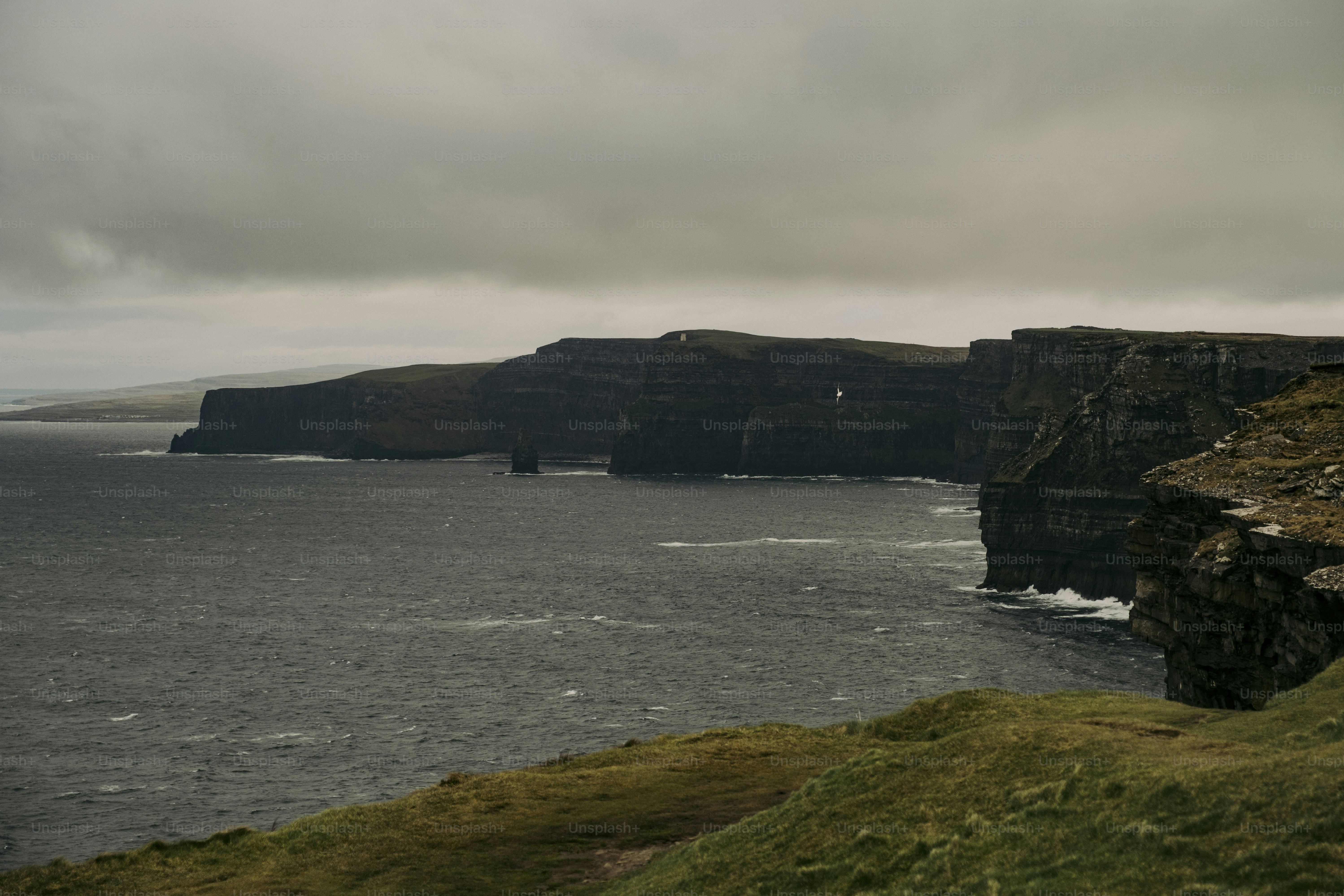 Uma pessoa em pé em um penhasco com vista para um corpo de água