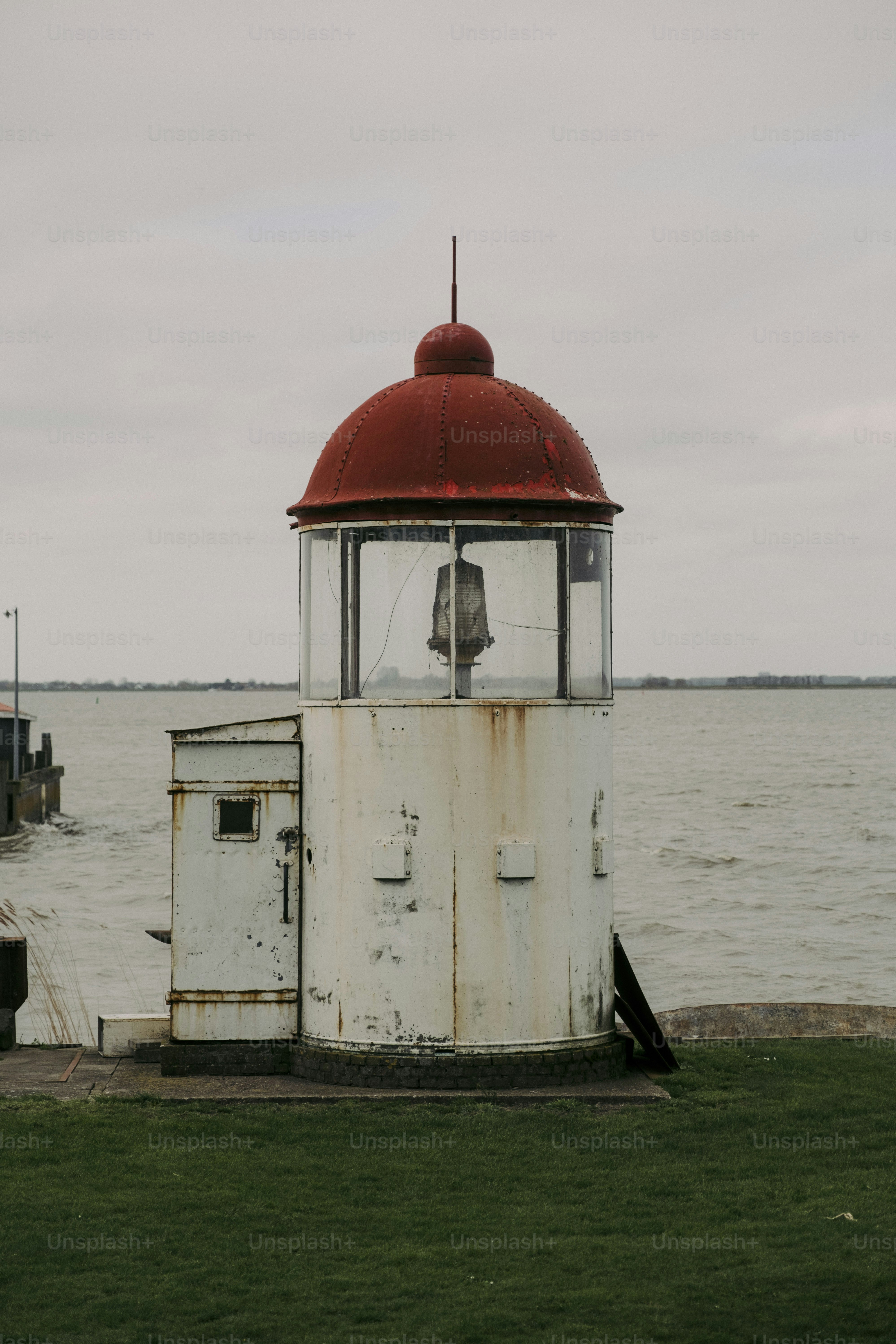 A white and red tower sitting on top of a lush green field