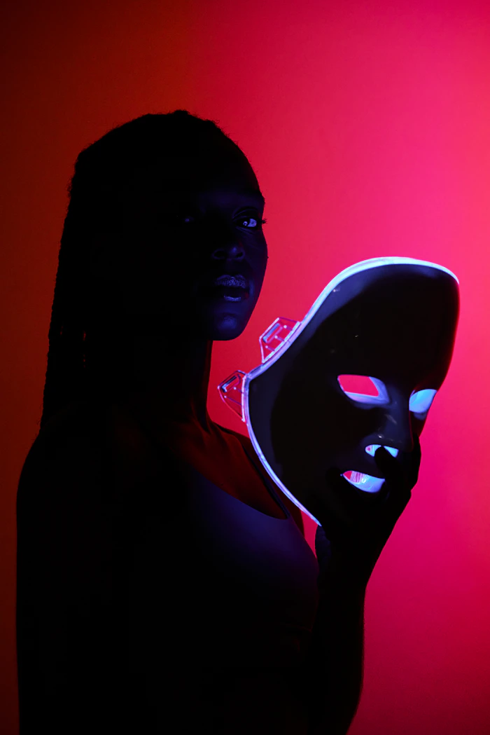 Femme tenant un masque LED de luminothérapie devant son visage