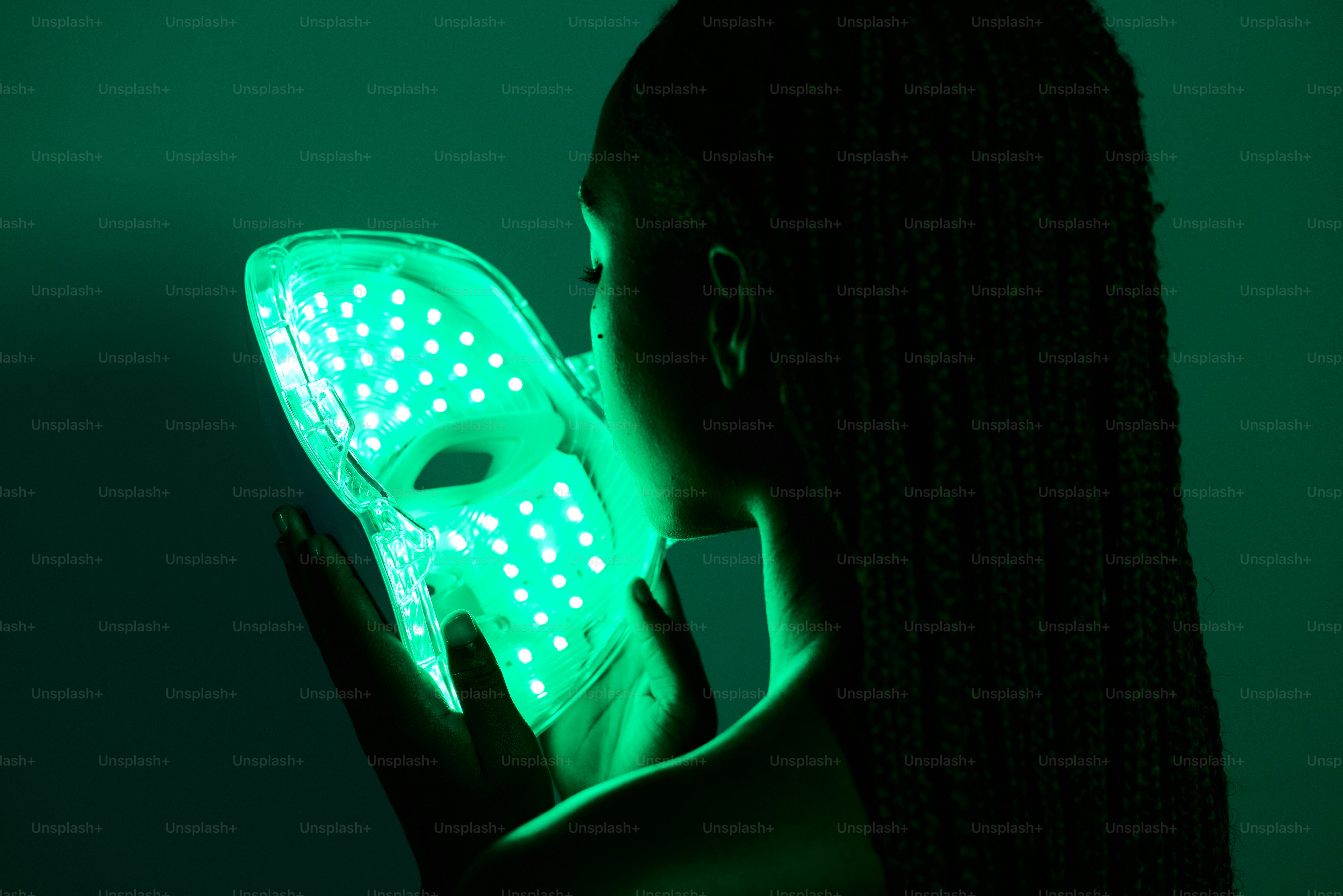 A woman holding a green light up mask