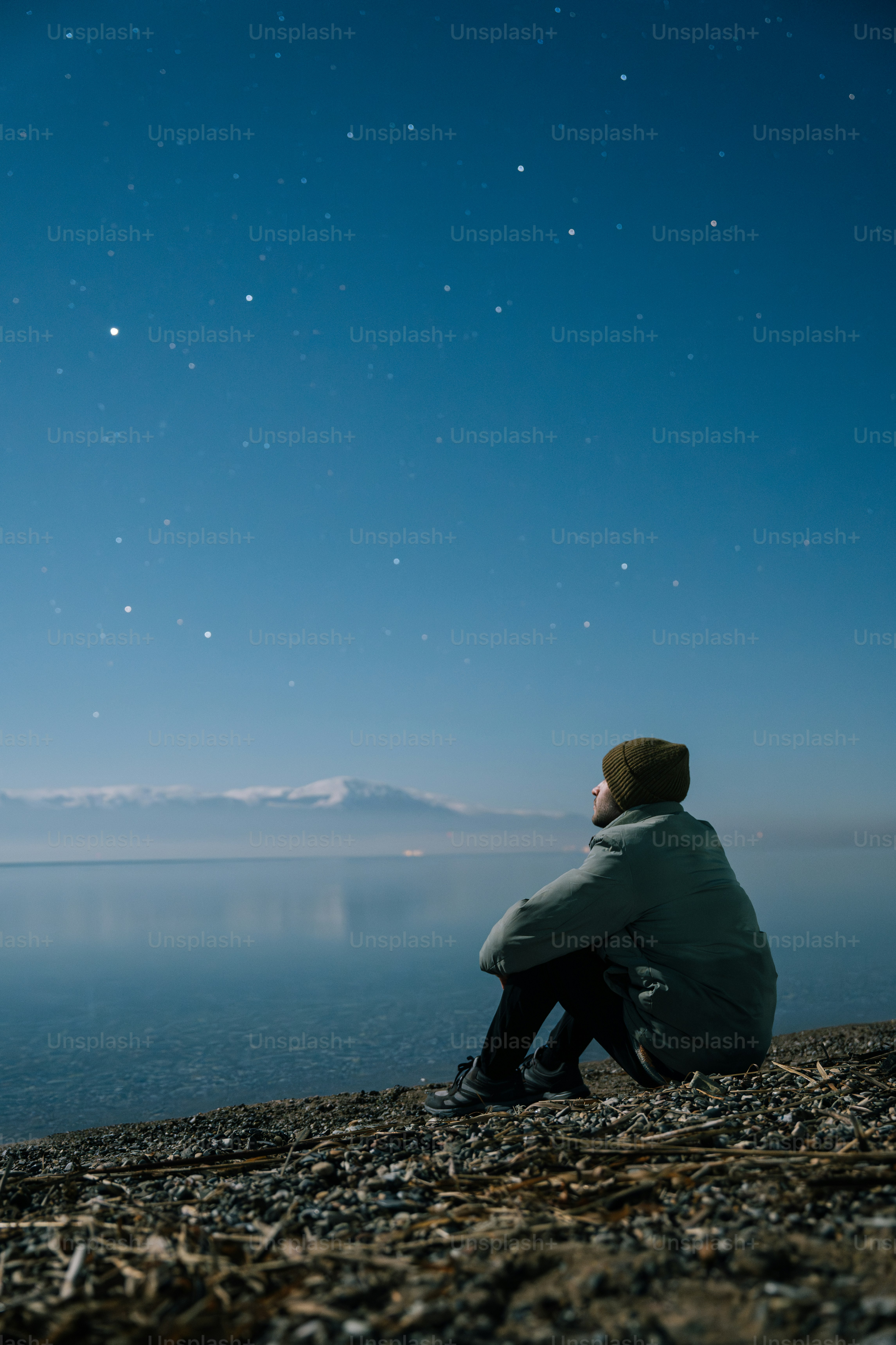 A man sitting on a beach watching the stars