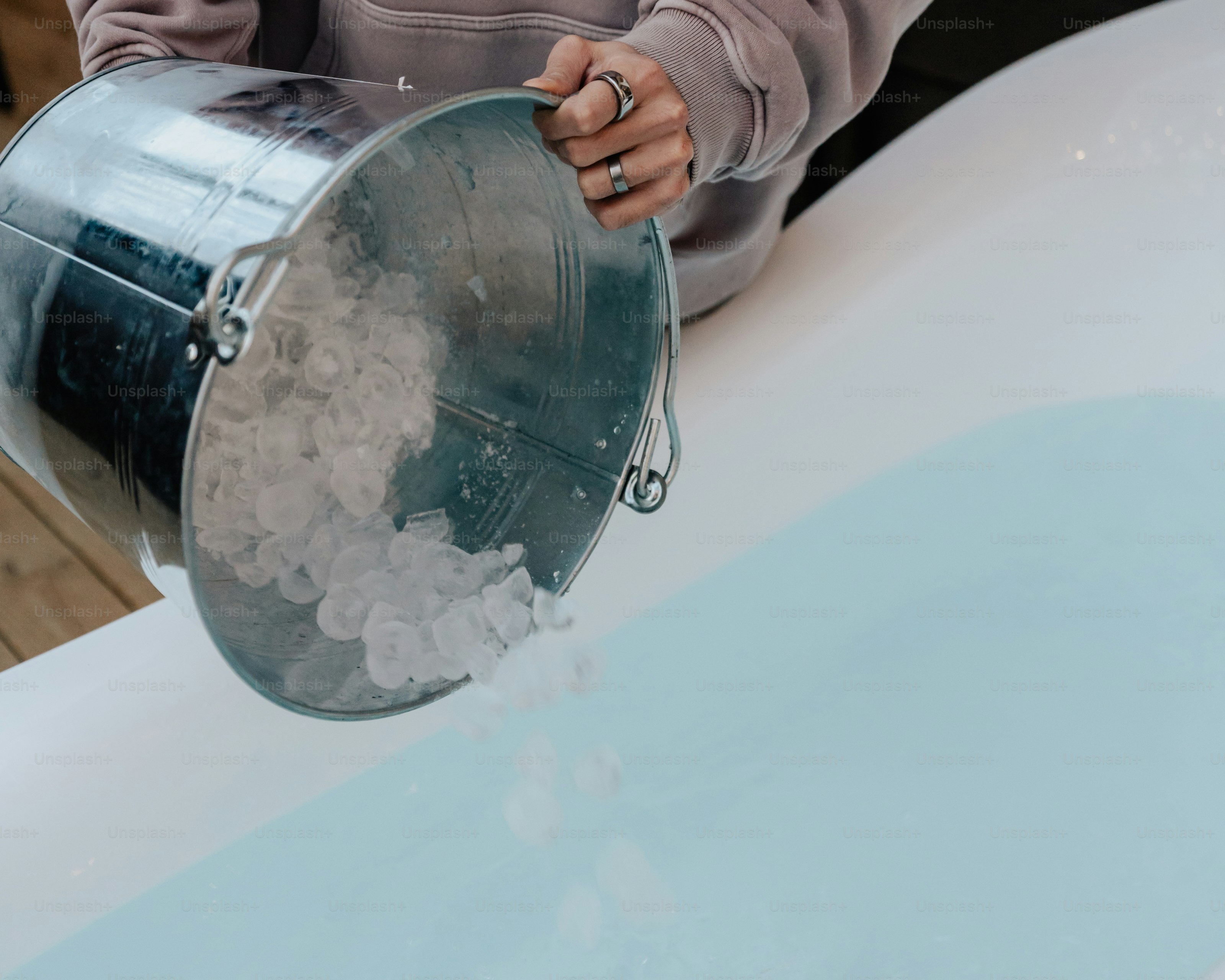 A woman pouring water into a bucket on top of a table
