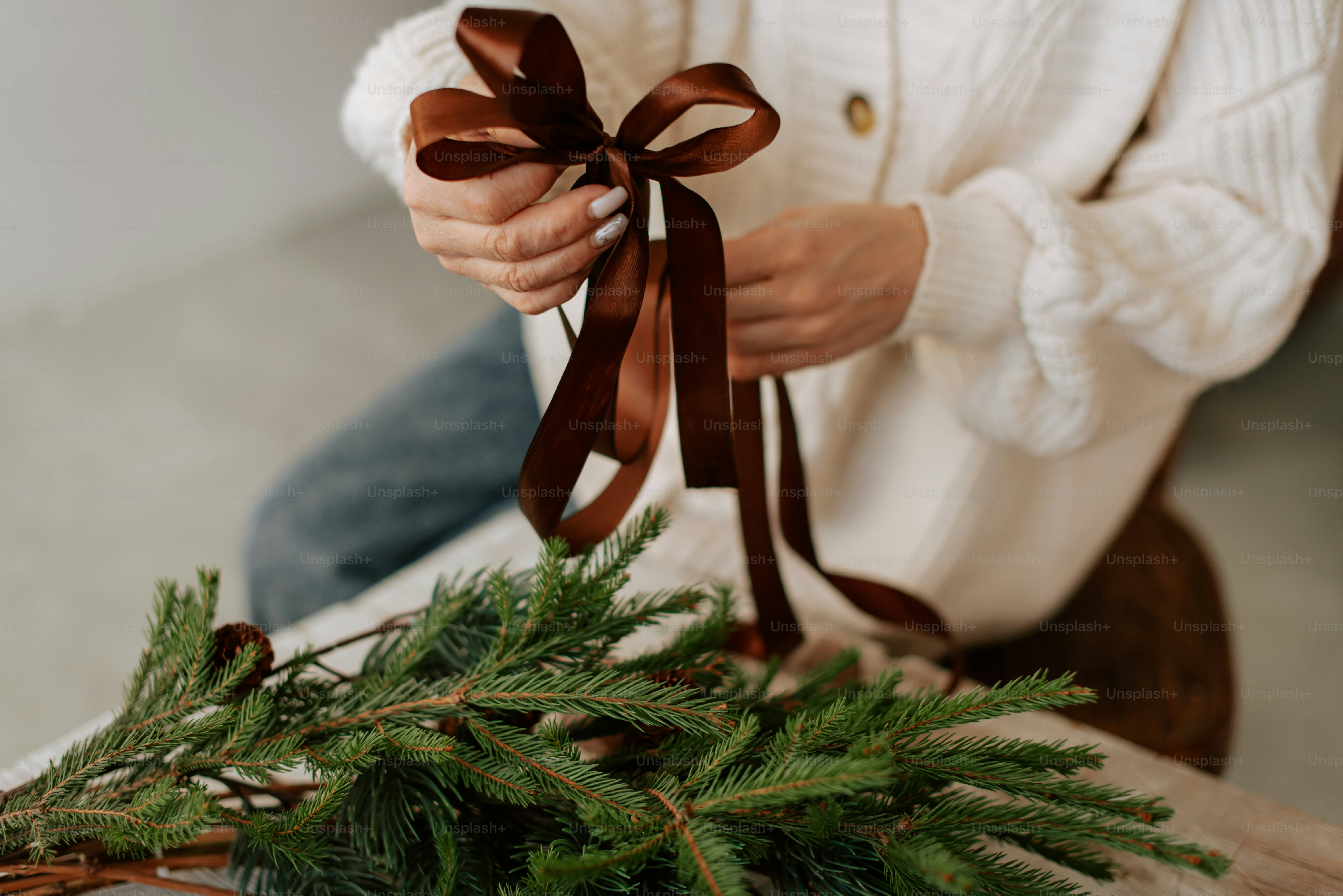 Une femme tenant un ruban brun au sommet d’un arbre de Noël