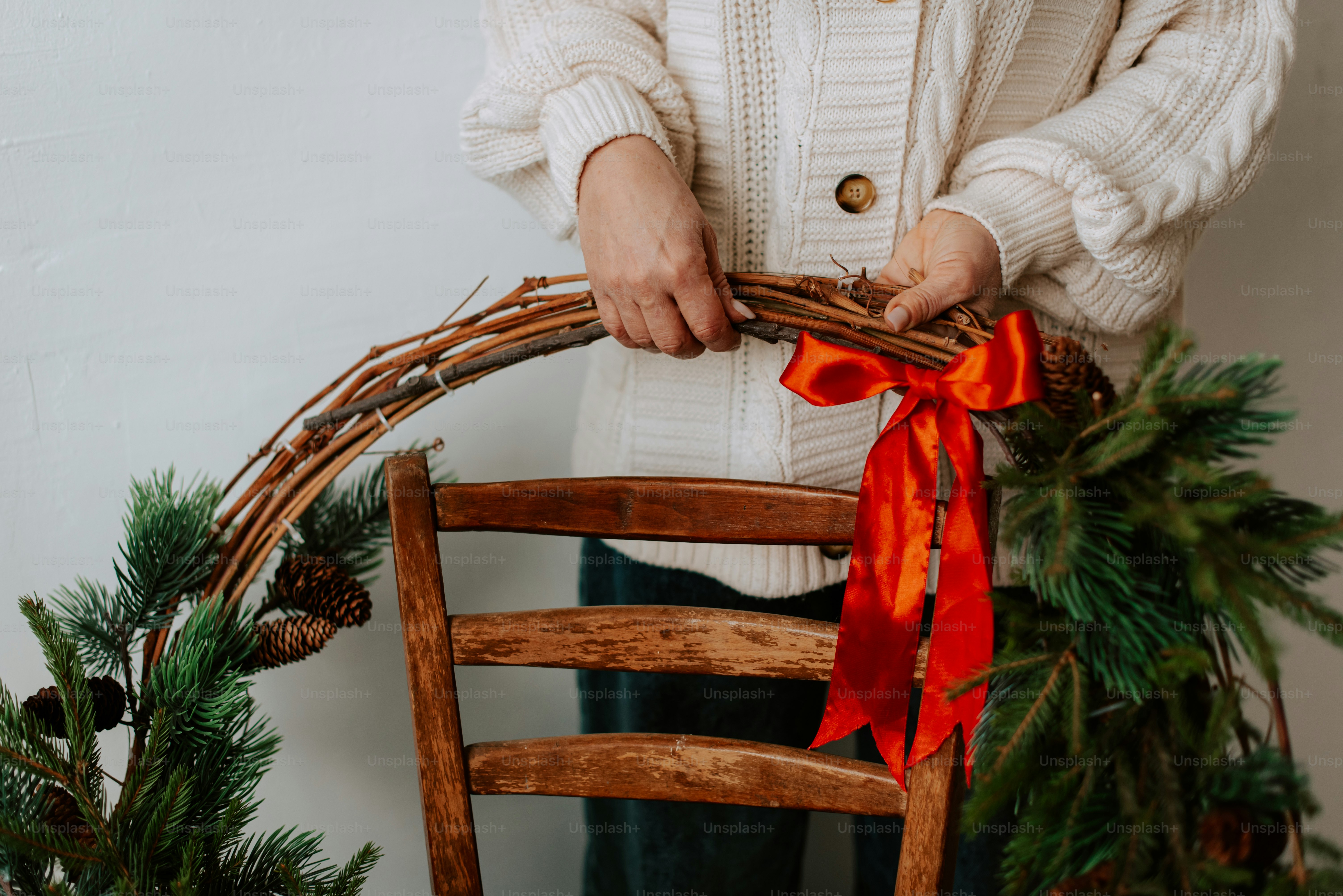 Une femme debout à côté d’une chaise tenant une couronne de Noël