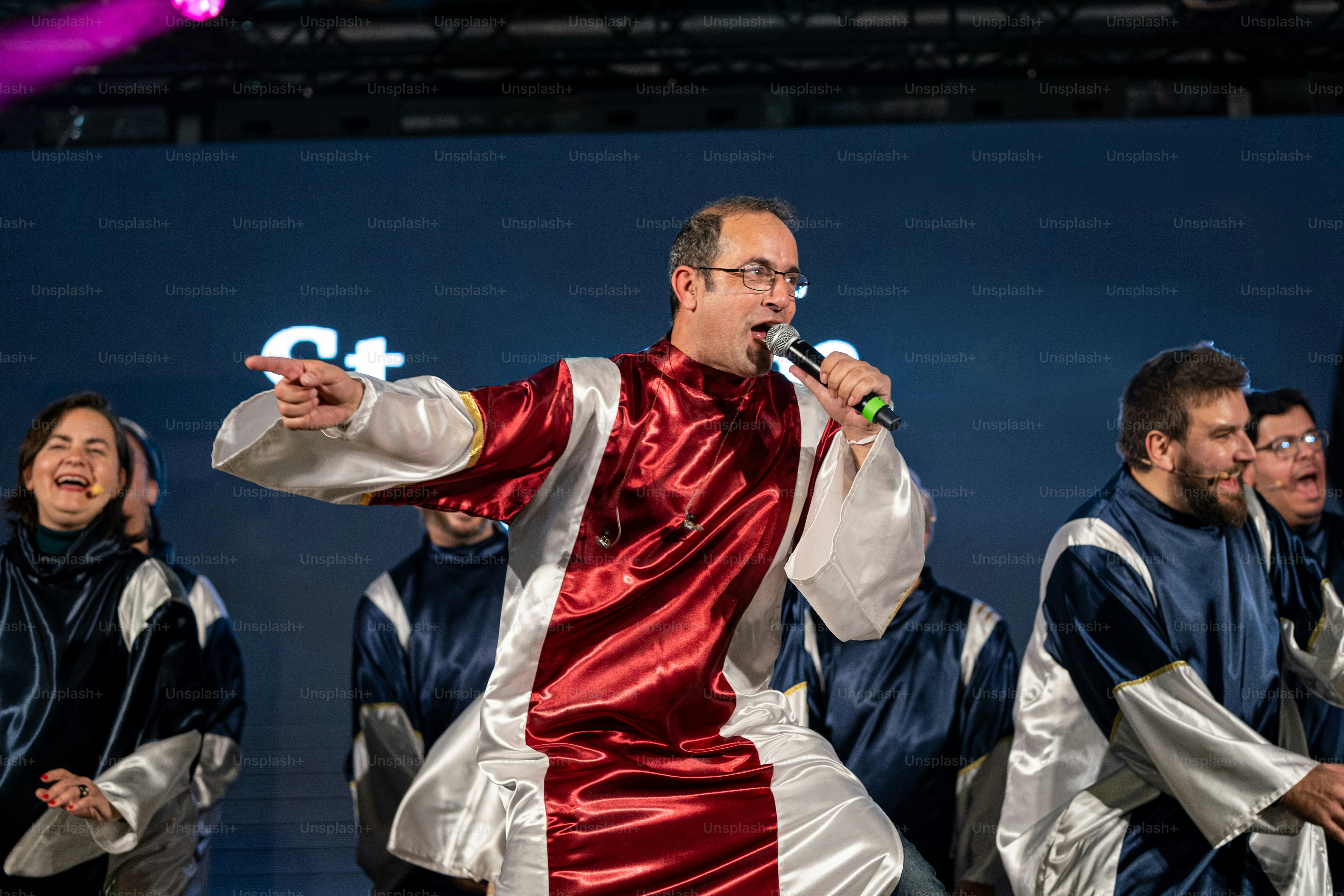 Um homem em uma roupa vermelha e prata cantando em um microfone