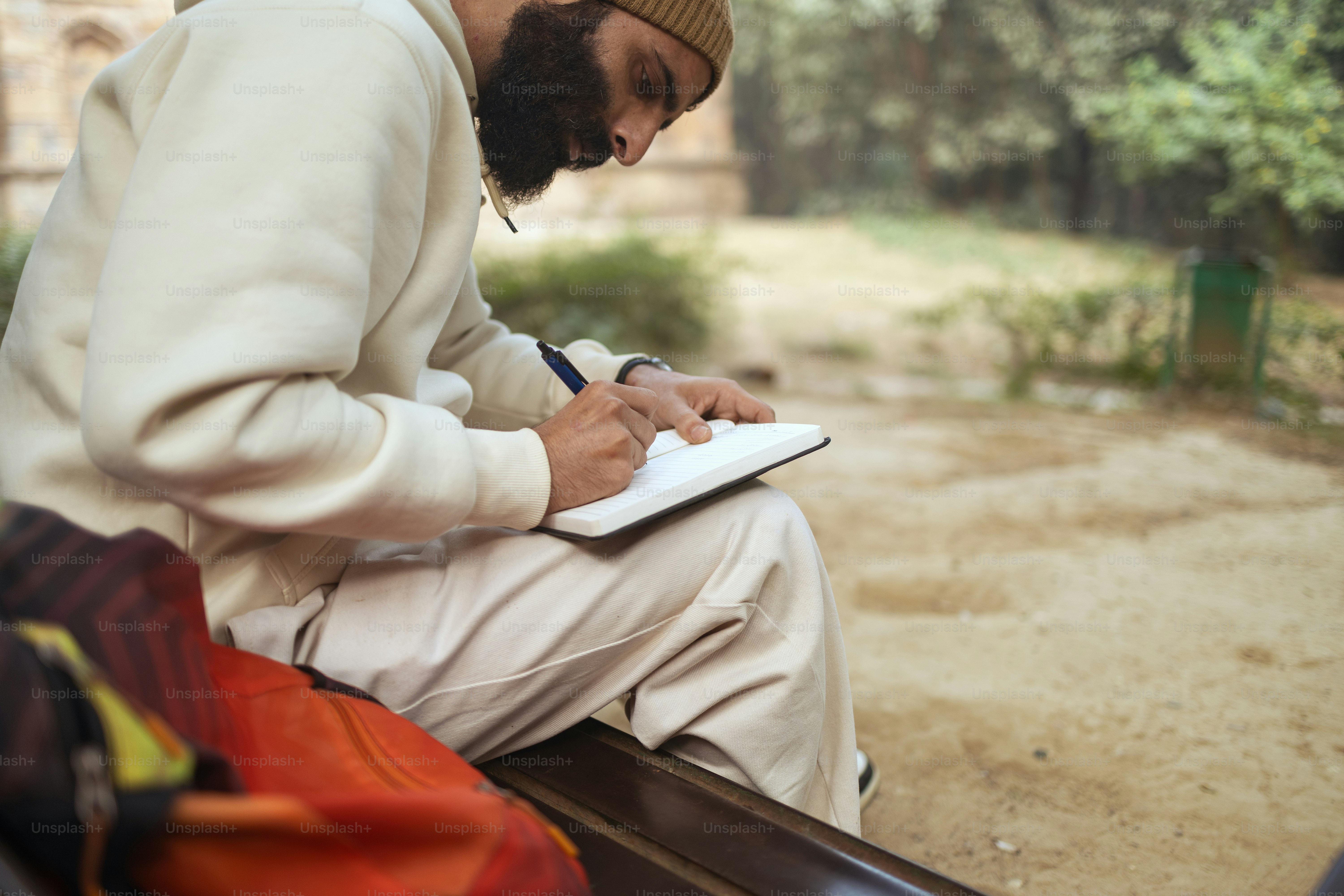 A man sitting on a bench writing on a piece of paper