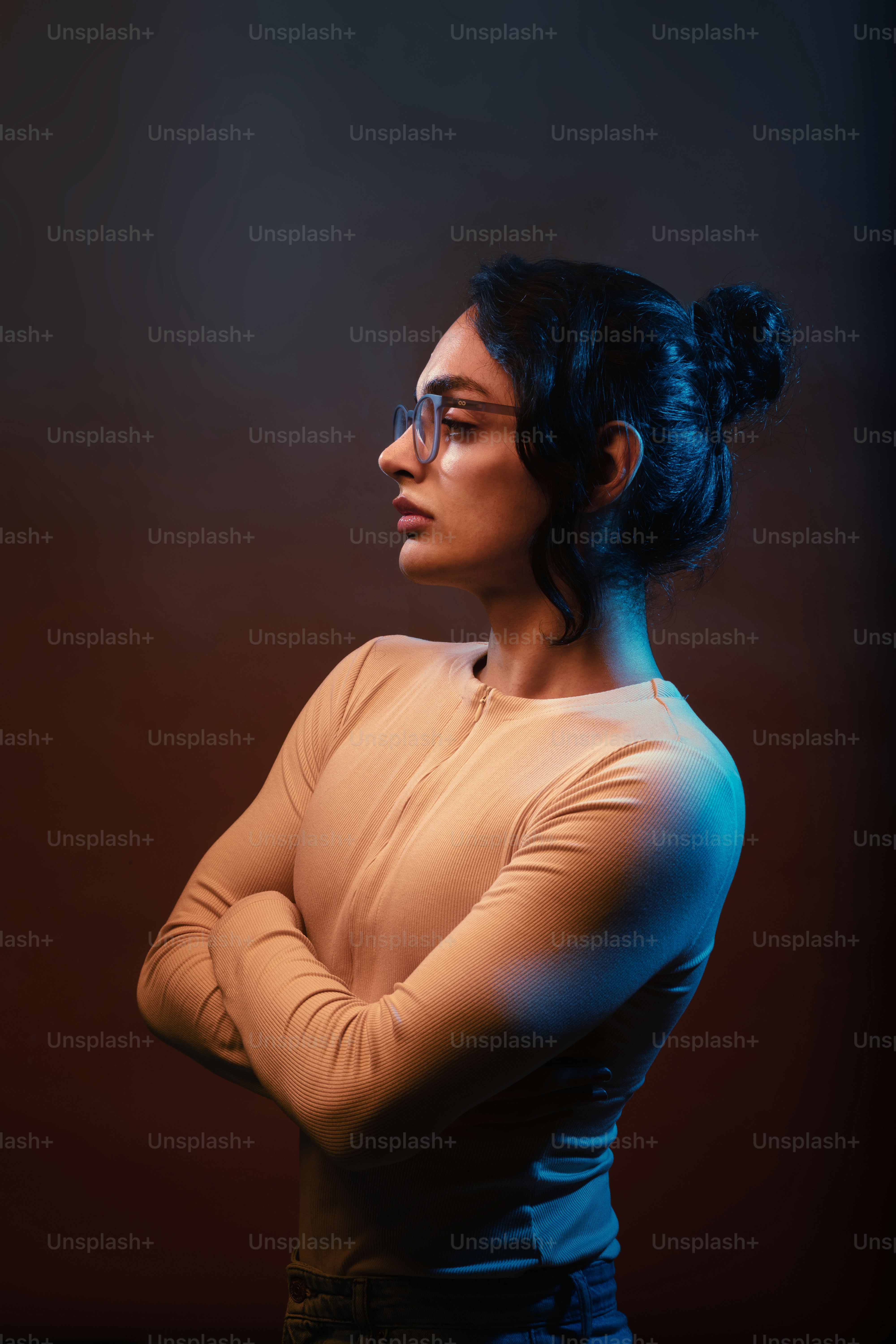 A woman with her arms crossed standing in front of a dark background ...