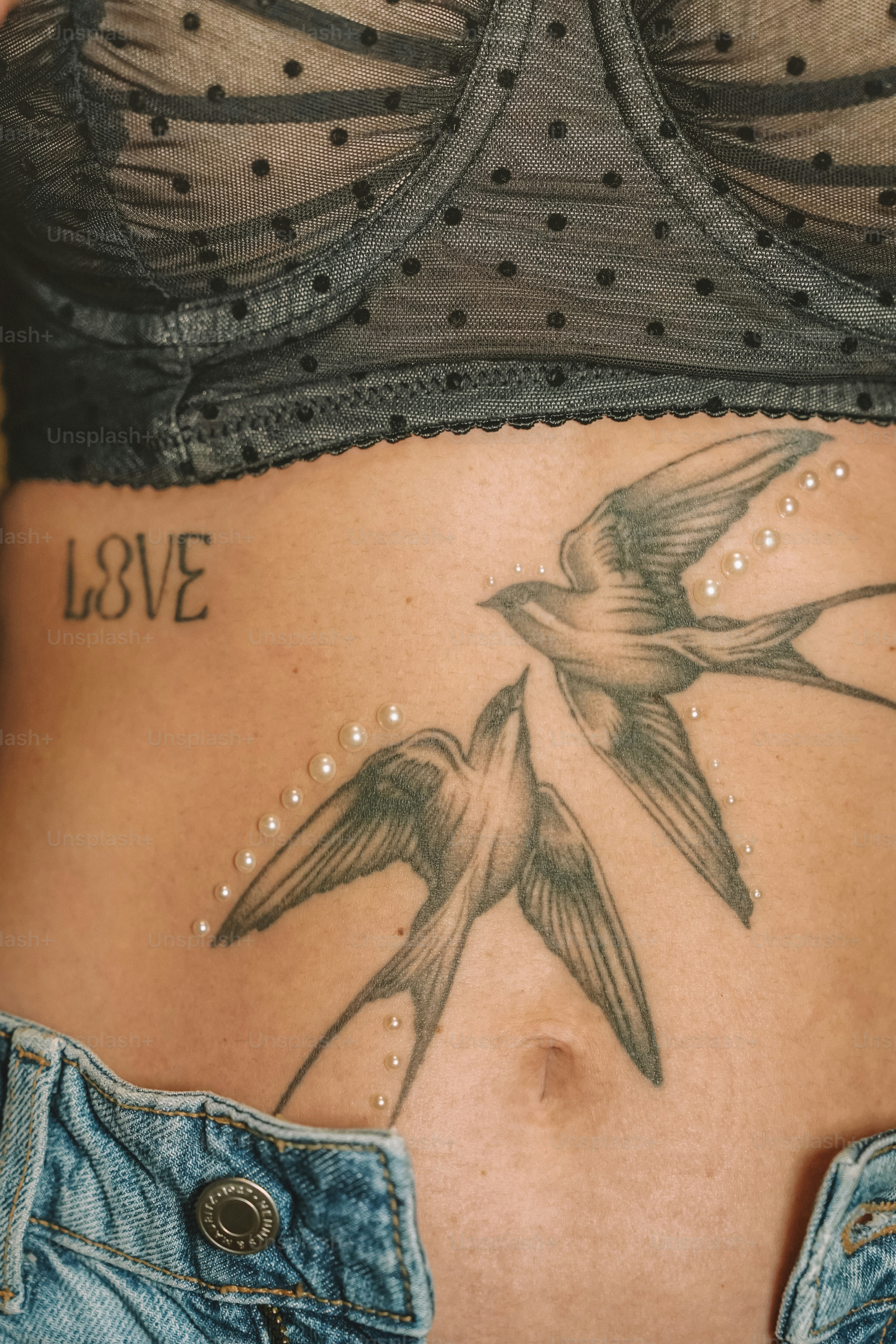Eine Frau mit einem Vogeltattoo auf dem Bauch
