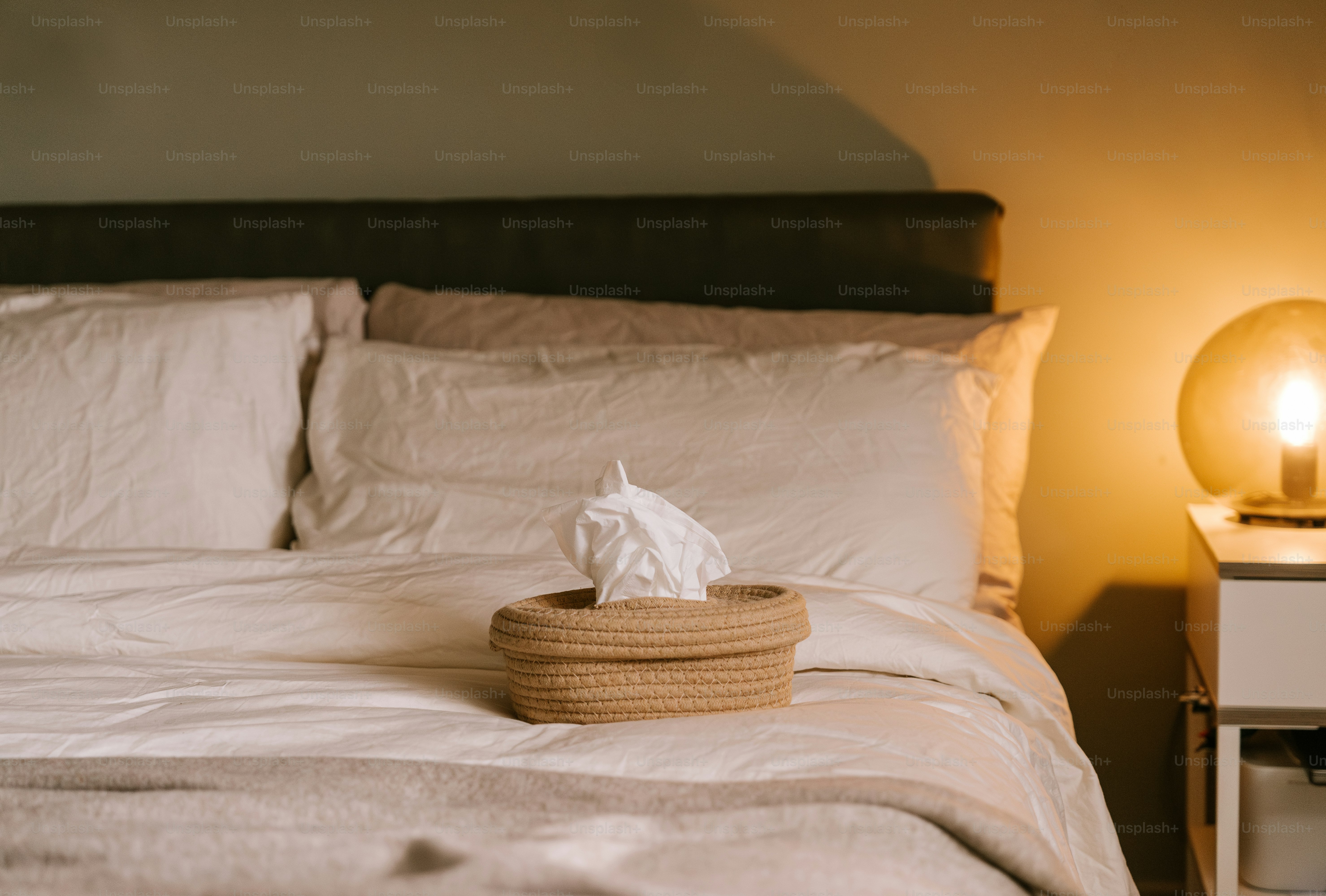 A bed with a white comforter and a basket on it