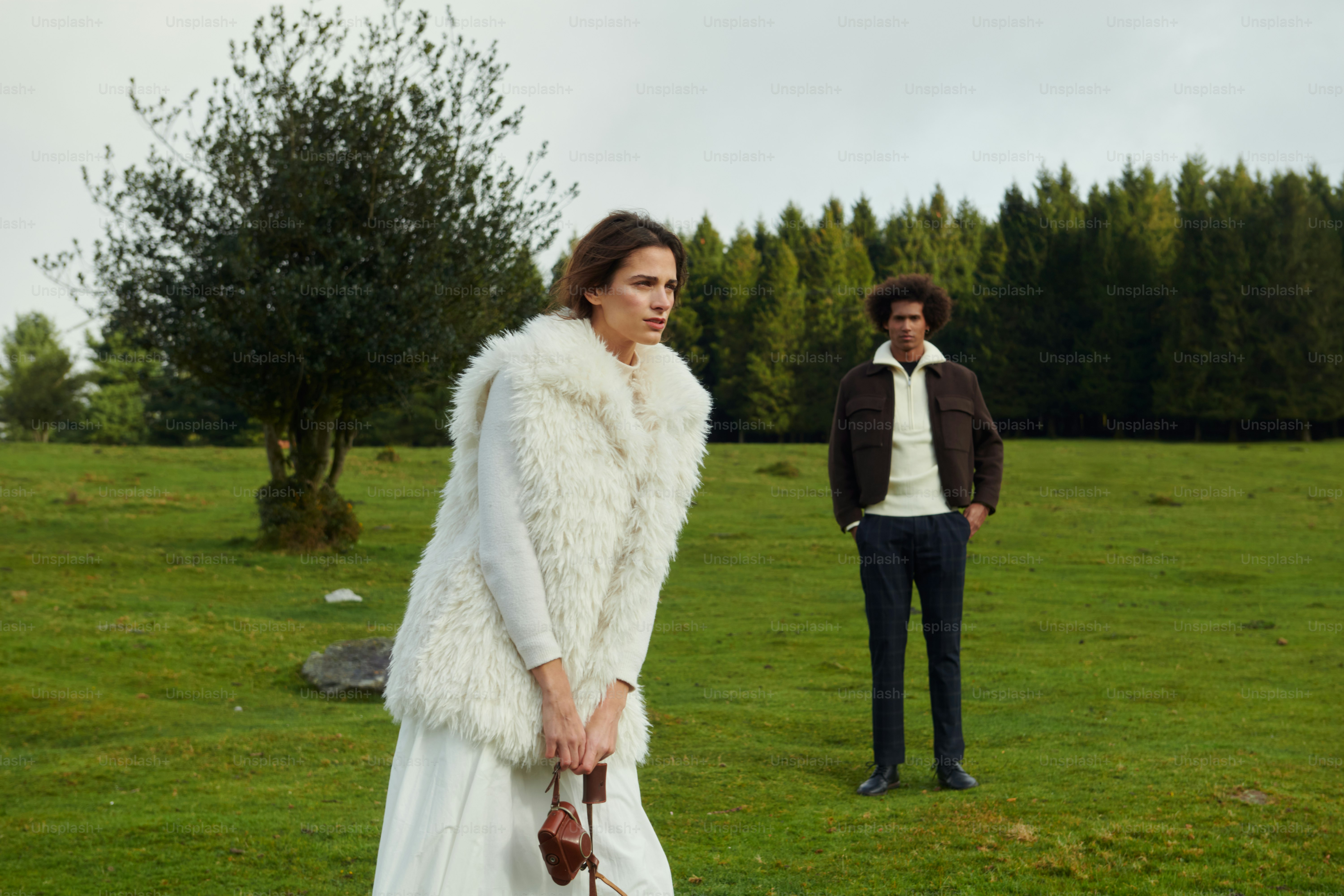 Eine Frau in einem weißen Kleid und ein Mann in einer schwarzen Jacke auf einem Feld