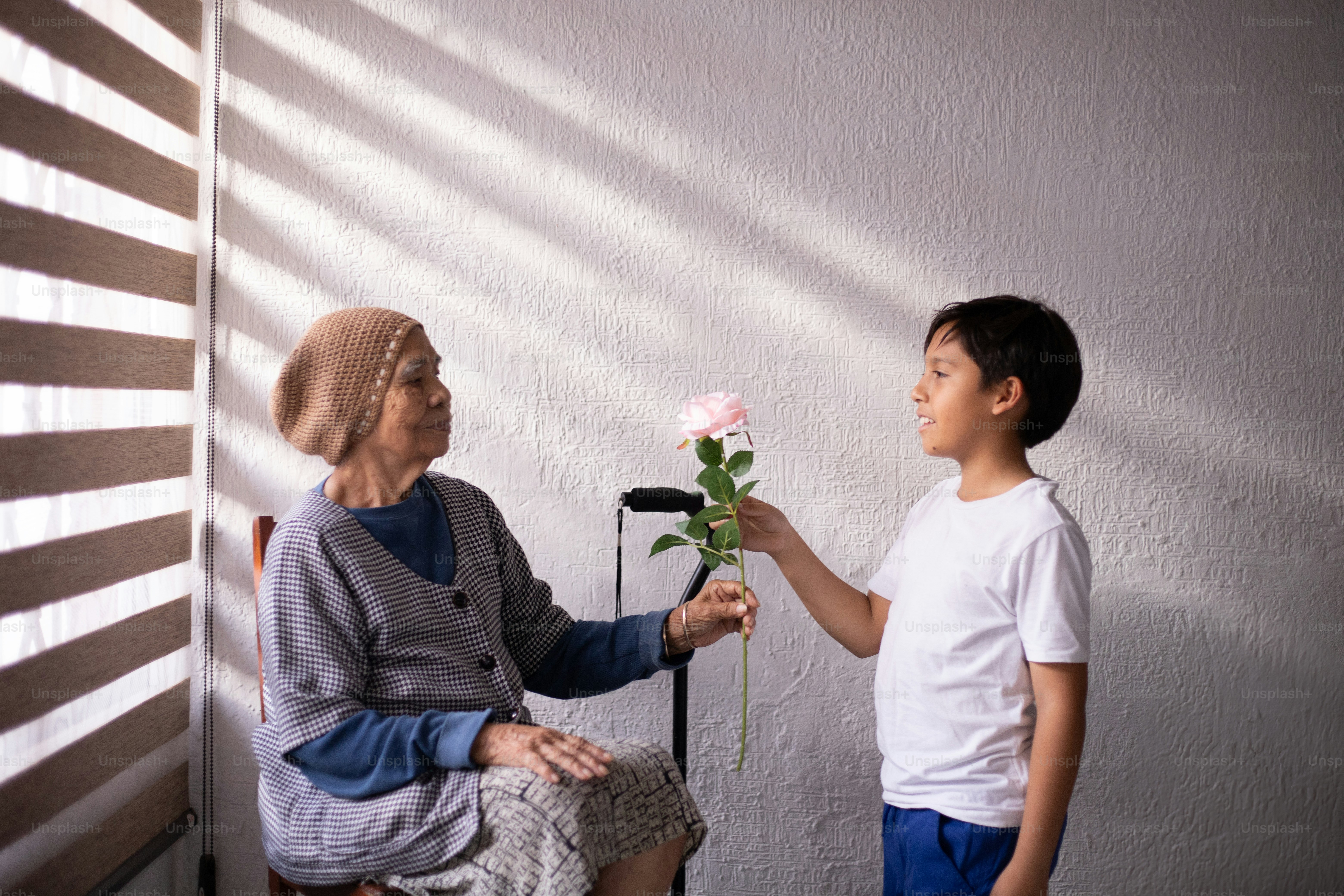 Un ragazzino che dà un fiore a una donna anziana