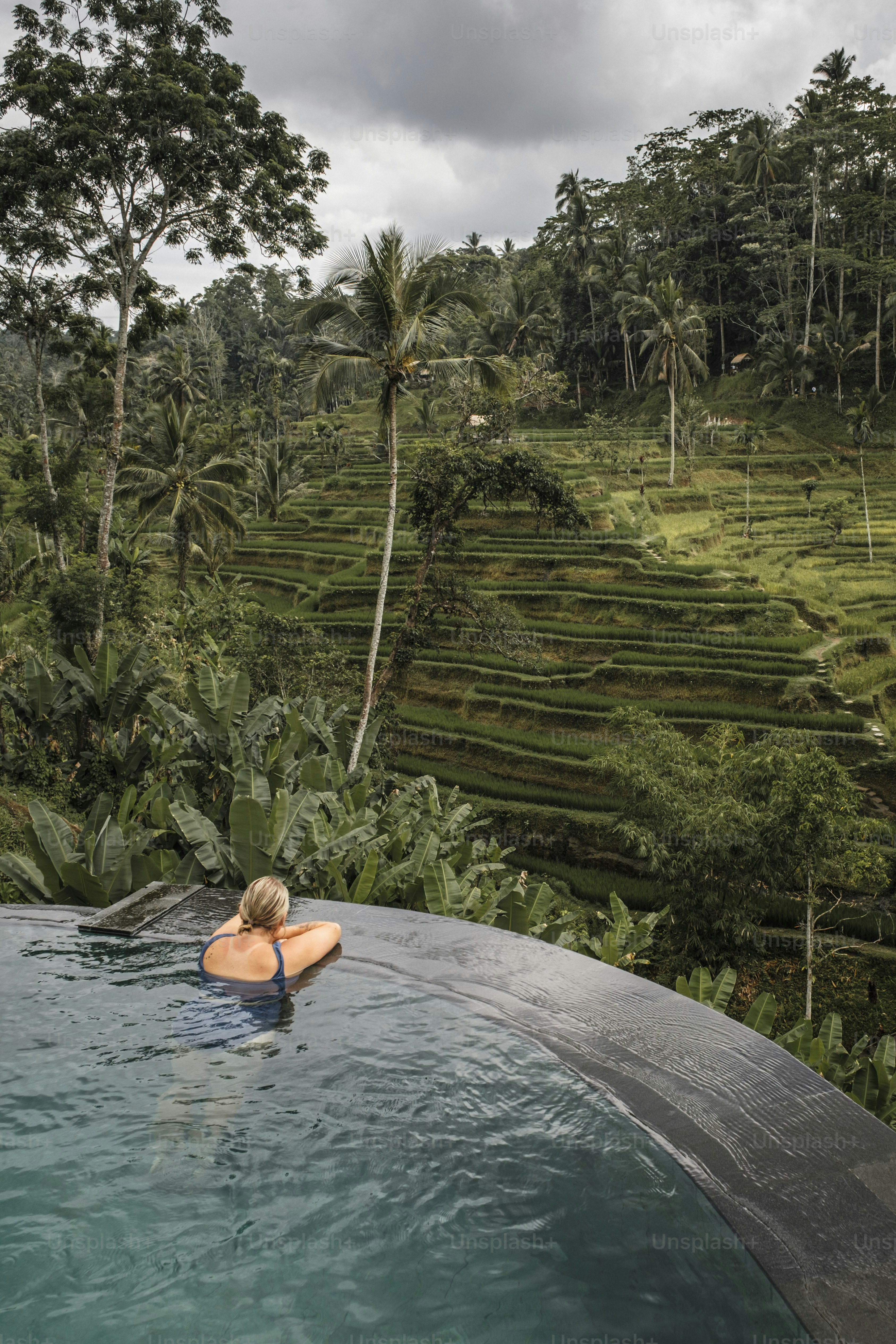 Una donna in una piscina circondata da alberi