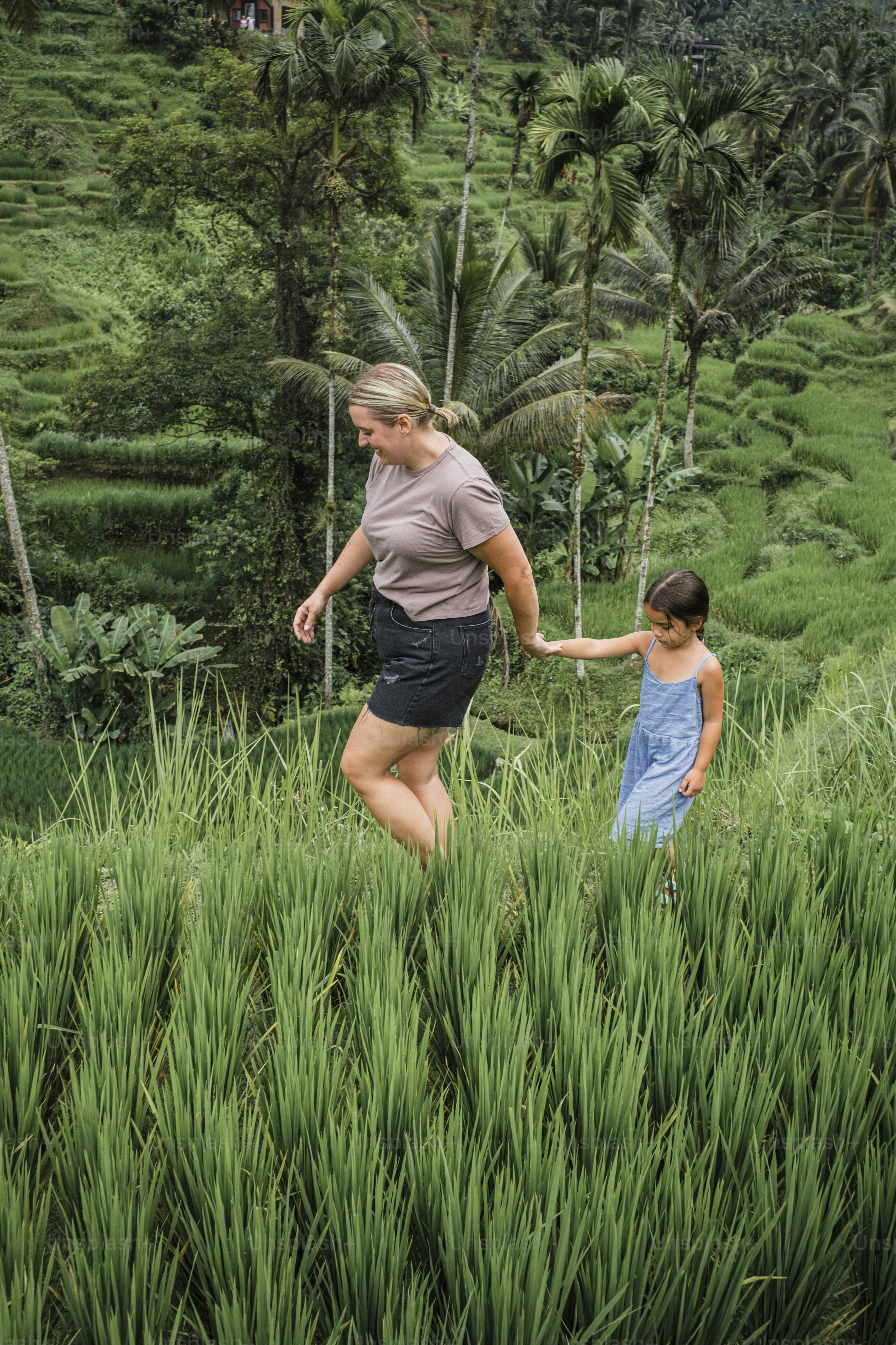 A woman and a young girl walking through a lush green field